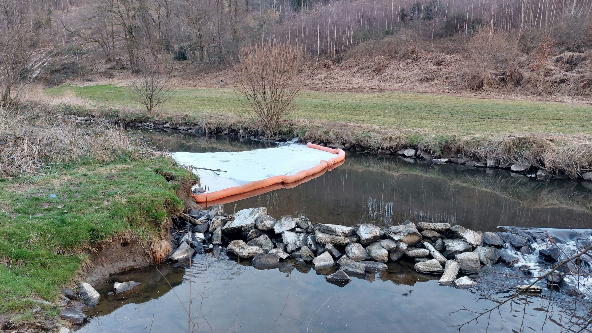 Ein weißer Teppich mit orangefarbenem Rand liegt auf dem Fluss.
