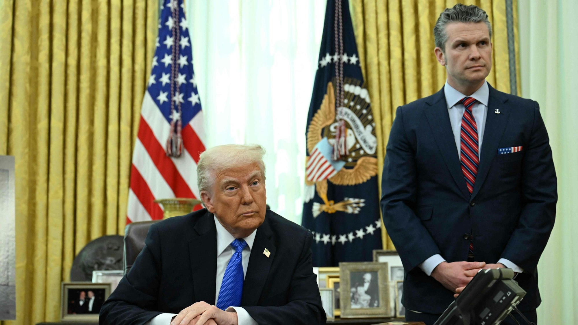(FILES) US President Donald Trump and Secretary of Defense Pete Hegseth listen during an event in the Oval Office of the White House in Washington, DC, on March 21, 2025. A US journalist was inadvertently included in a group chat in which Defense Secretary Pete Hegseth, Vice President JD Vance and other top officials discussed upcoming strikes against Yemen's Huthi rebels, the White House confirmed on March 24, 2025. (Photo by Annabelle Gordon / AFP)