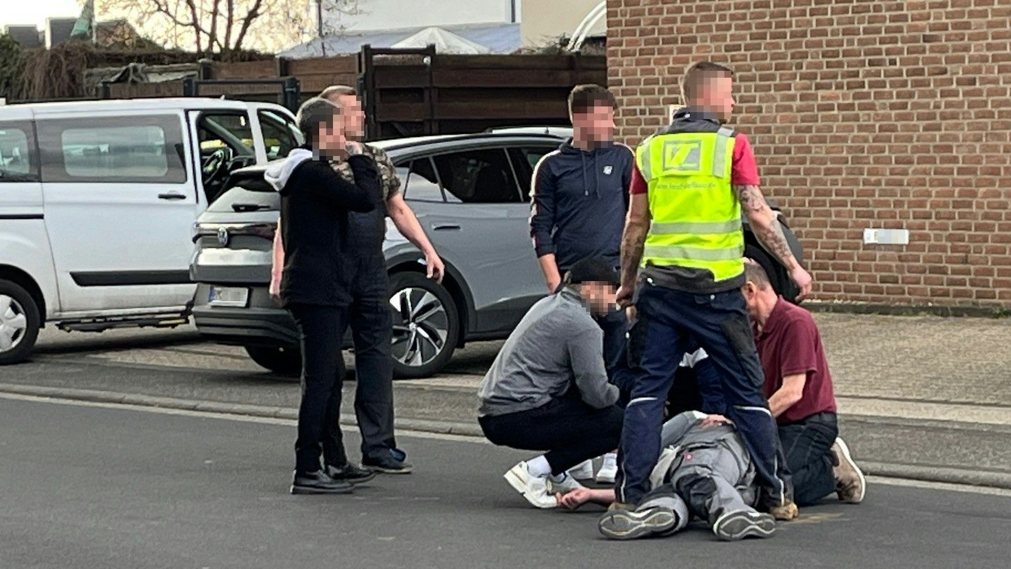 Auf dem Foto sind mehrere Männer zu sehen, die sich um einen verletzten Mann kümmern.