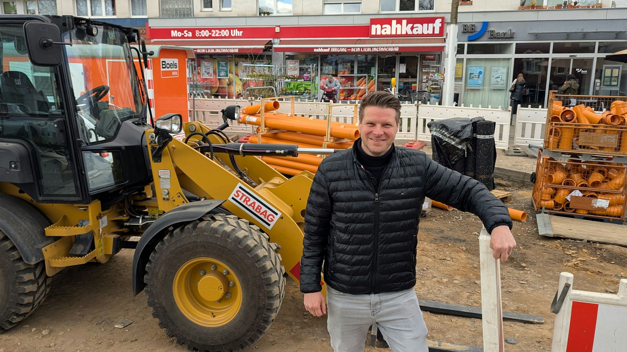 Das Foto zeigt den Nahkauf-Inhaber vor einem Radlader auf der Baustelle vor seinem Geschäft.