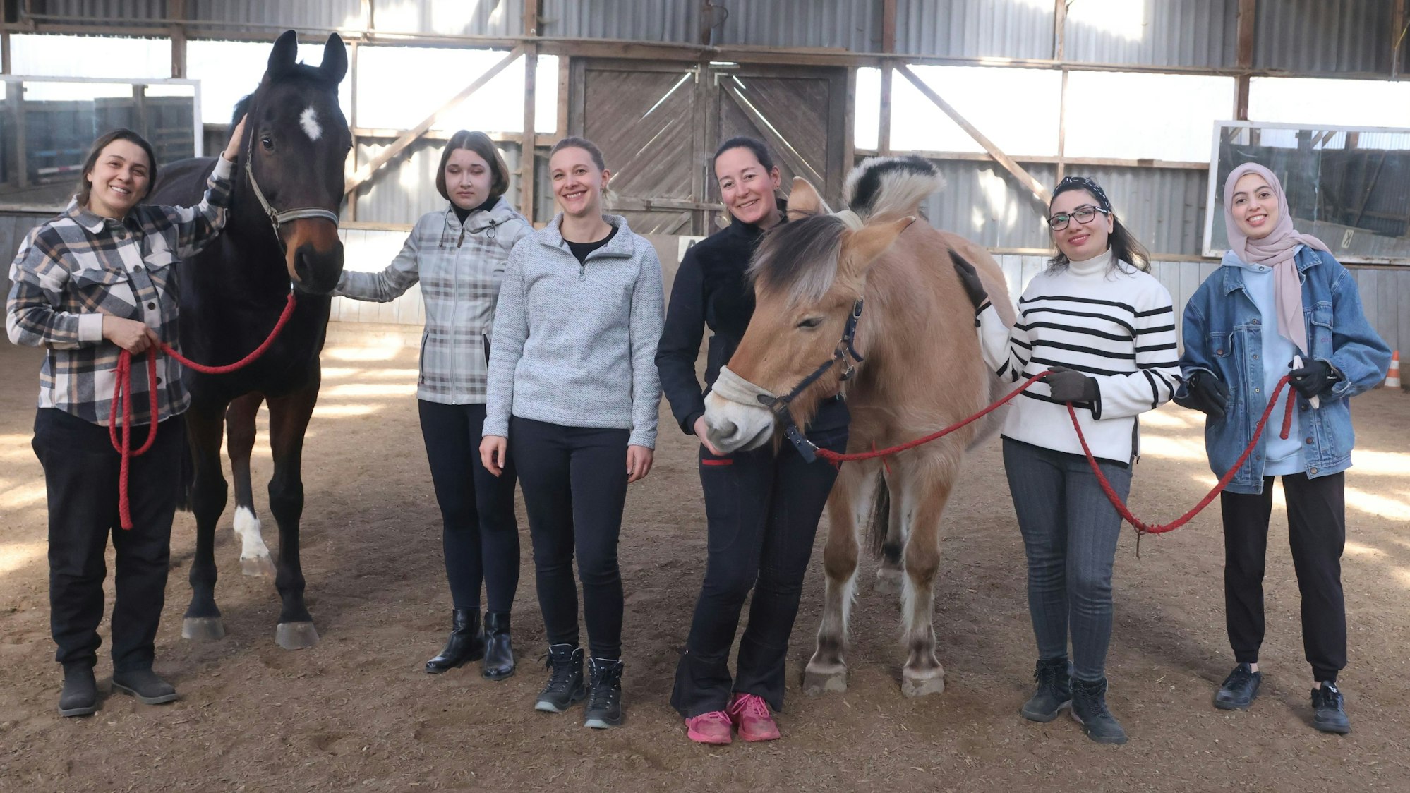 In der Reithalle in Waldbröl-Happach lehrten Janine Schüttenhelm (Mitte, links) und Simone Hannewald (Mitte, rechts) zugewanderten Frauen den richtigen Umgang mit Pferden. Anlass war ein Projekt der Caritas Oberberg.