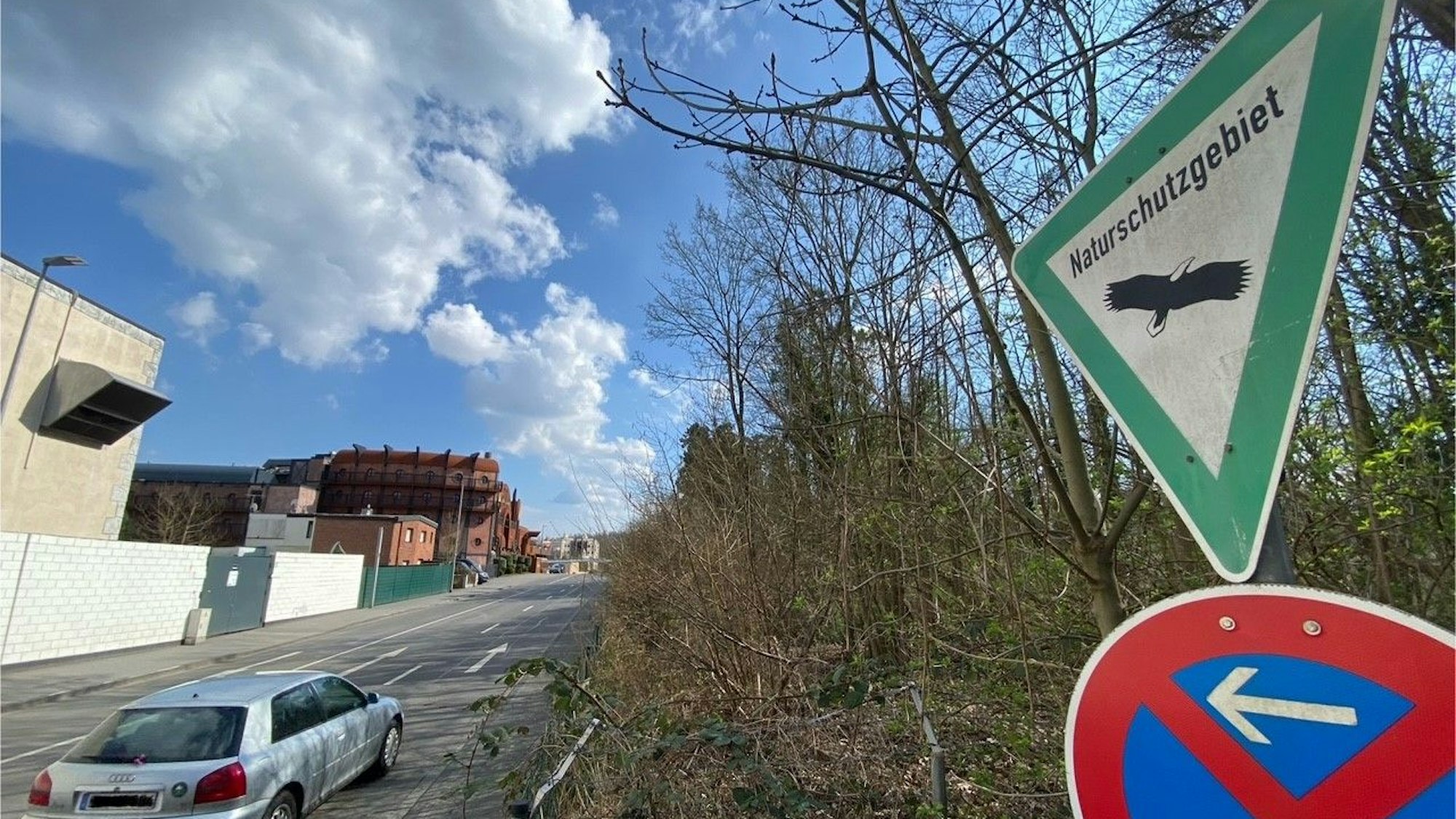 Zu sehen ist ein Schild, das auf das Naturschutzgebiet hinweist. Im Hintergrund ist das zum Phantasialand gehörende Hotel Charles Lindbergh zu sehen.