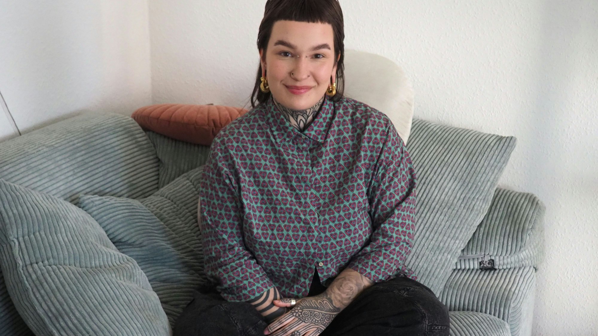 Laura Gertz sitzt im Schneidersitz auf einer Couch.