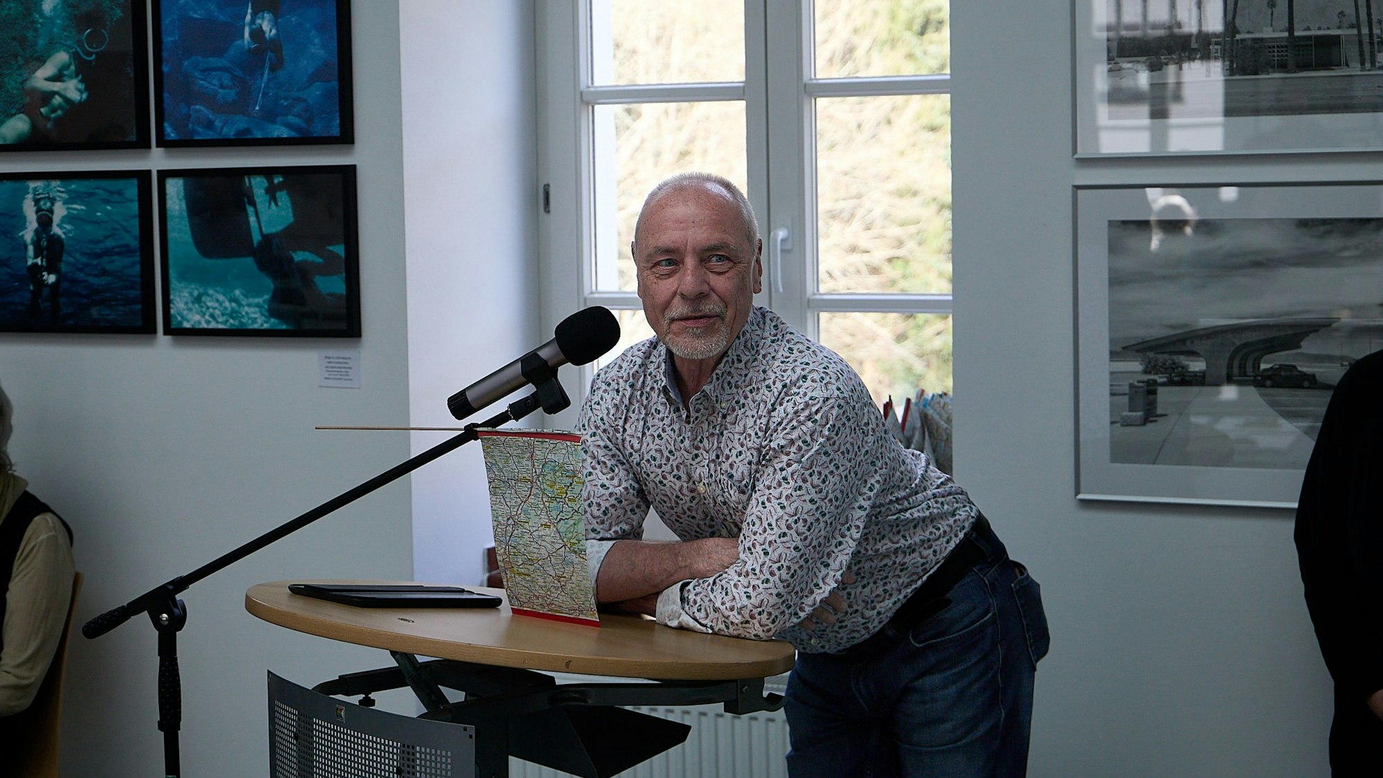Rainer Martens stützt sich im Kunstforum Eifel in Gemünd mit verschränkten Armen auf einem Pult ab.