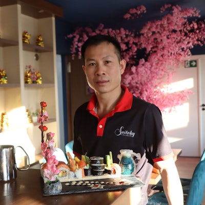 Zu sehen ist Nguyen van Loc, der eine Patte mit Sushi präsentiert.