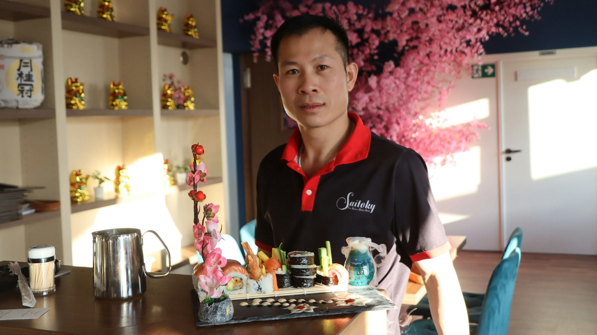 Zu sehen ist Nguyen van Loc, der eine Patte mit Sushi präsentiert.