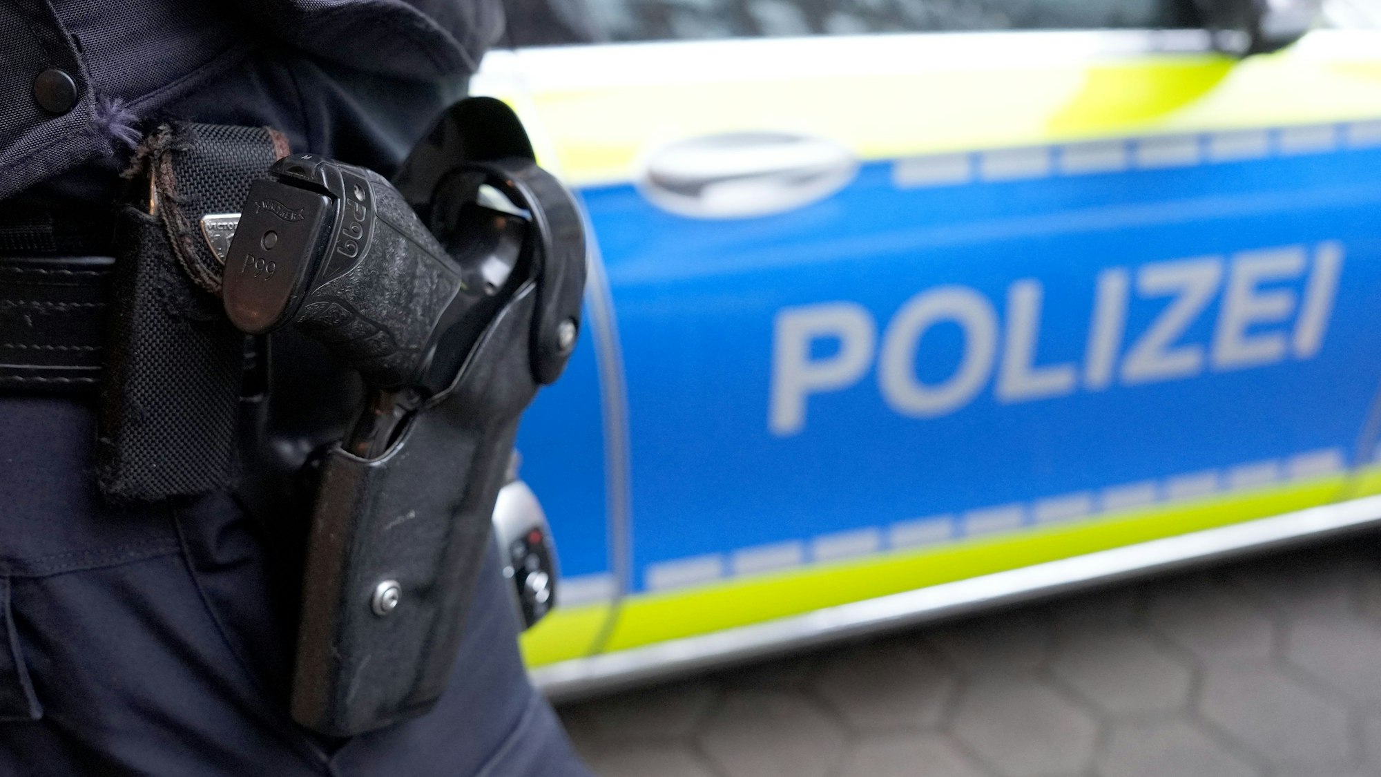 Das Foto zeigt einen Polizeibeamten vor einem Einsatzwagen.