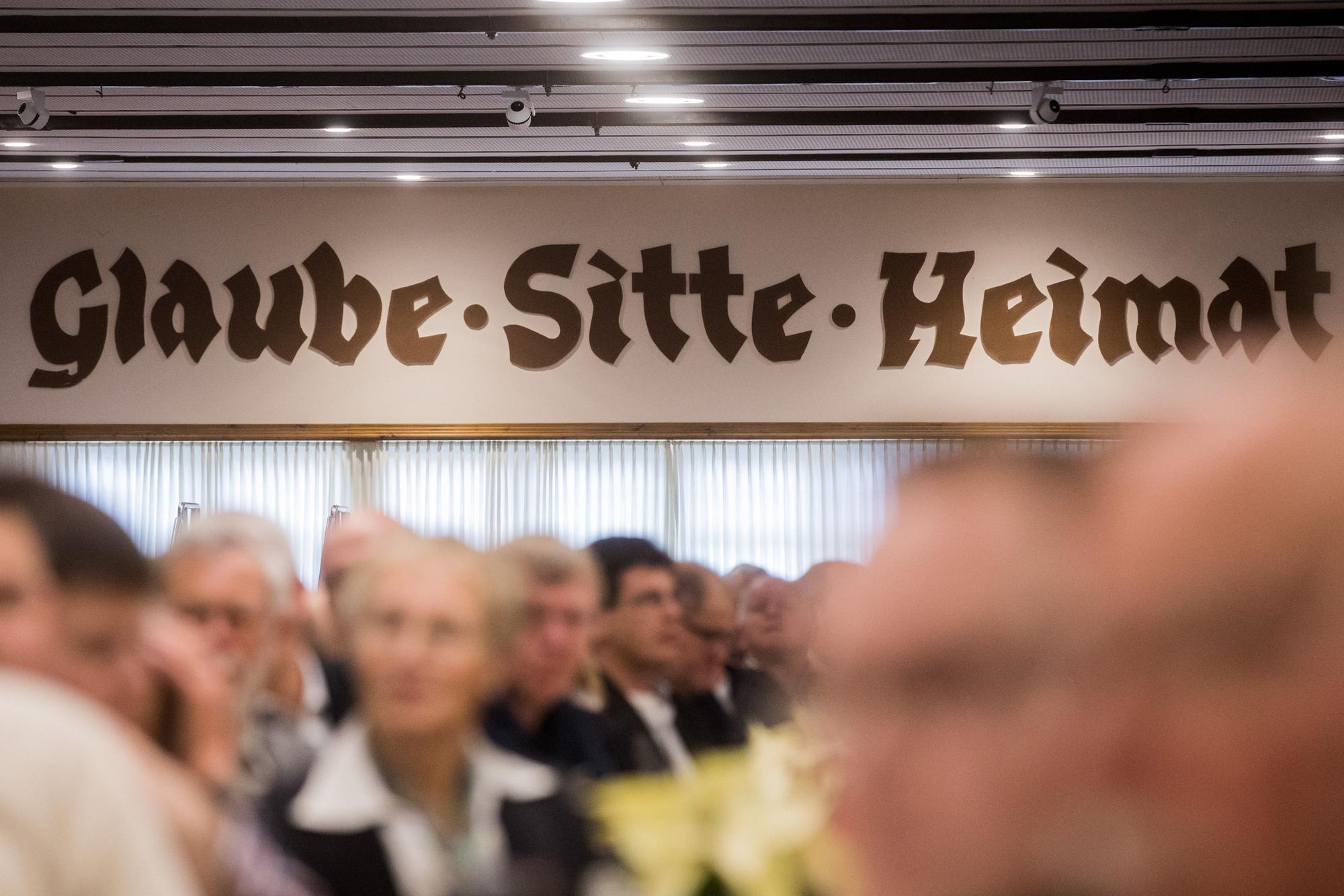 Arnsberg: „Glaube, Sitte, Heimat“ steht in der Schützenhalle der St. Sebastianus Schützenbrüderschaft über den Köpfen der Mitglieder.