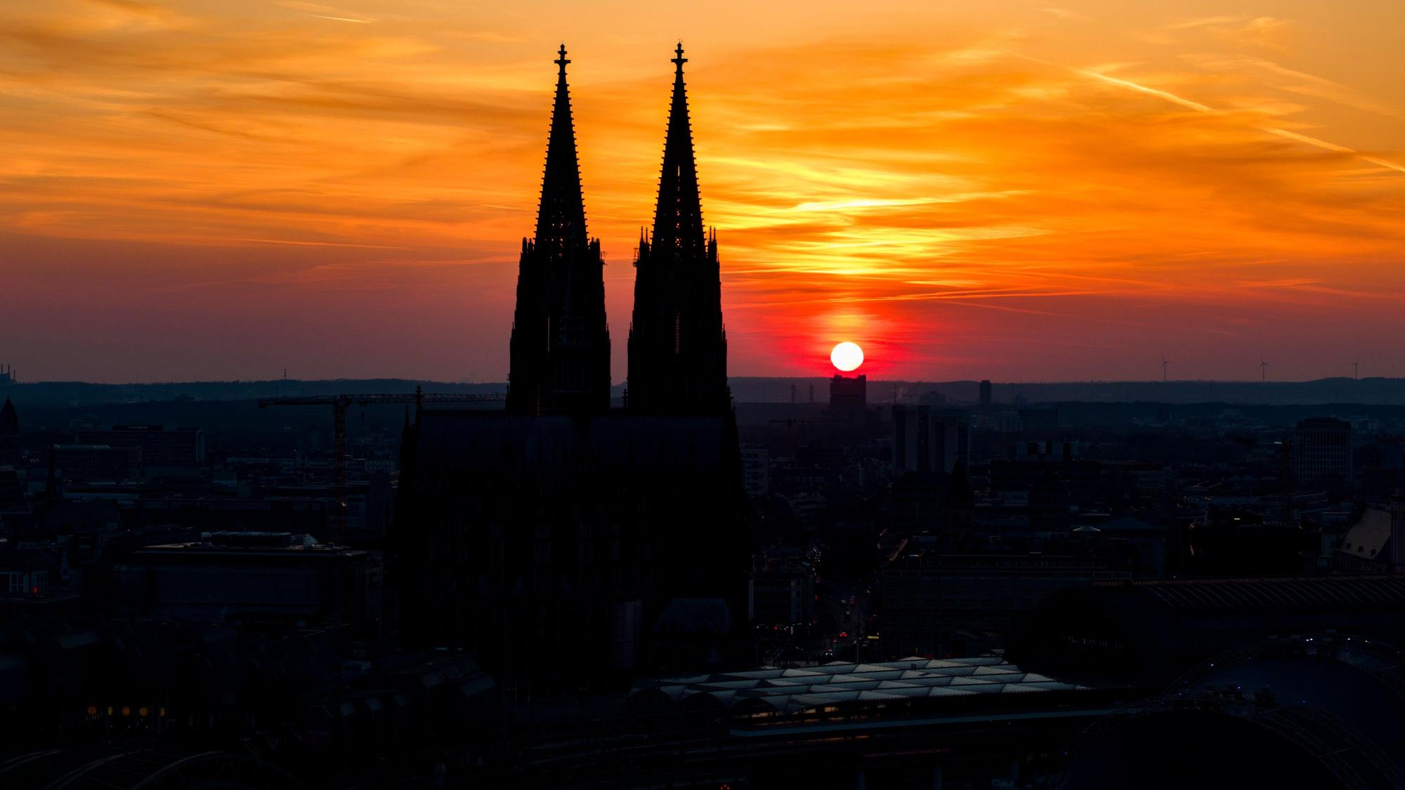 08.03.2025, Nordrhein-Westfalen, Köln: Die untergehende Sonne ist neben den Türmen vom Kölner Dom zu sehen. (Luftaufnahme mit einer Drohne) Foto: Christoph Reichwein/dpa +++ dpa-Bildfunk +++