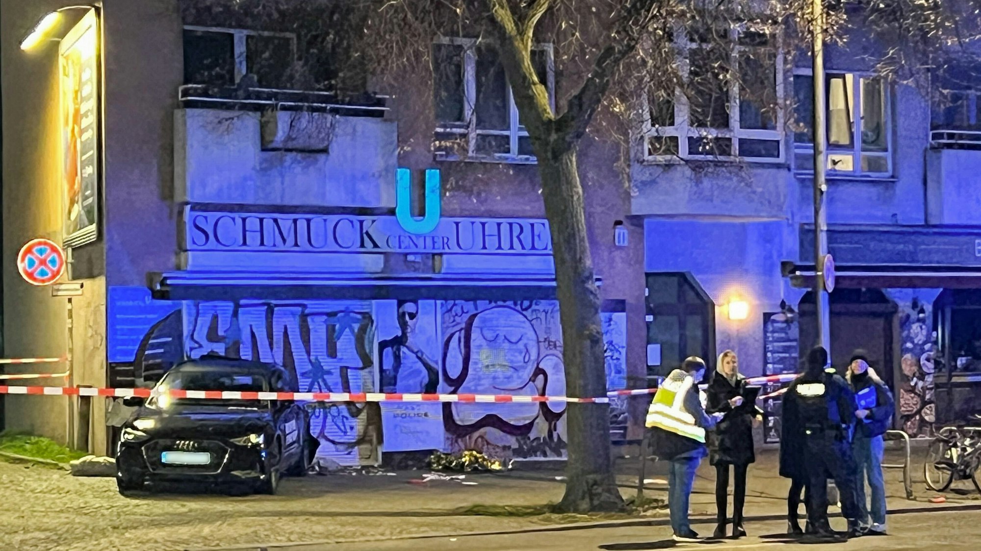 Berliner Polizisten besprechen sich neben einer Absperrung um ein Auto. Auf der Flucht vor einer Polizeikontrolle hat ein Jugendlicher mit einem Mietwagen mehrere Menschen verletzt.