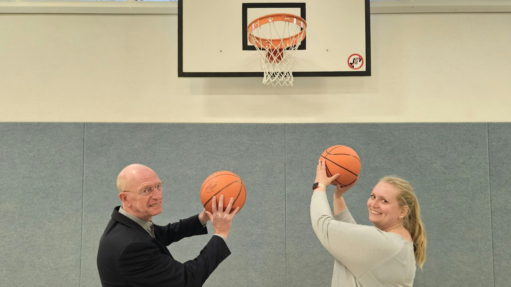 Ina Hölscher-Lange und Richard Fremerey stehen nebeneinander und zielen mit Bällen auf einen Basketballkorb.