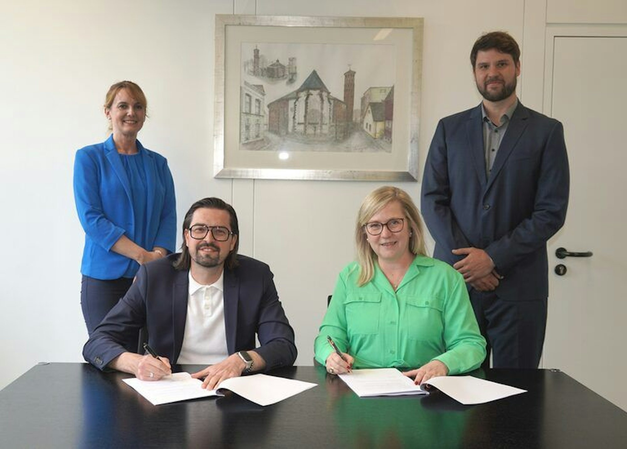 Auf dem Bild sind vier Personen an einem Schreibtisch im Rathaus zu sehen.