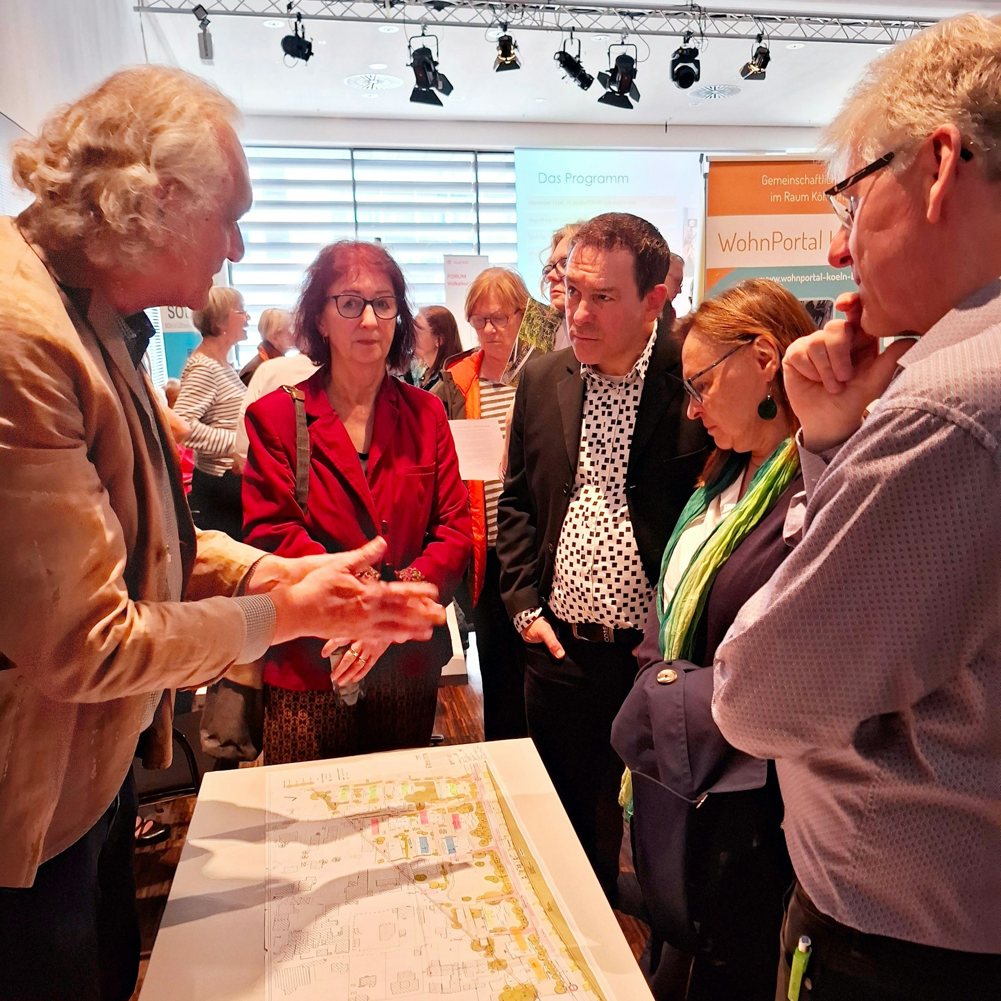 Menschen stehen um eine Wohnbauskizze herum.