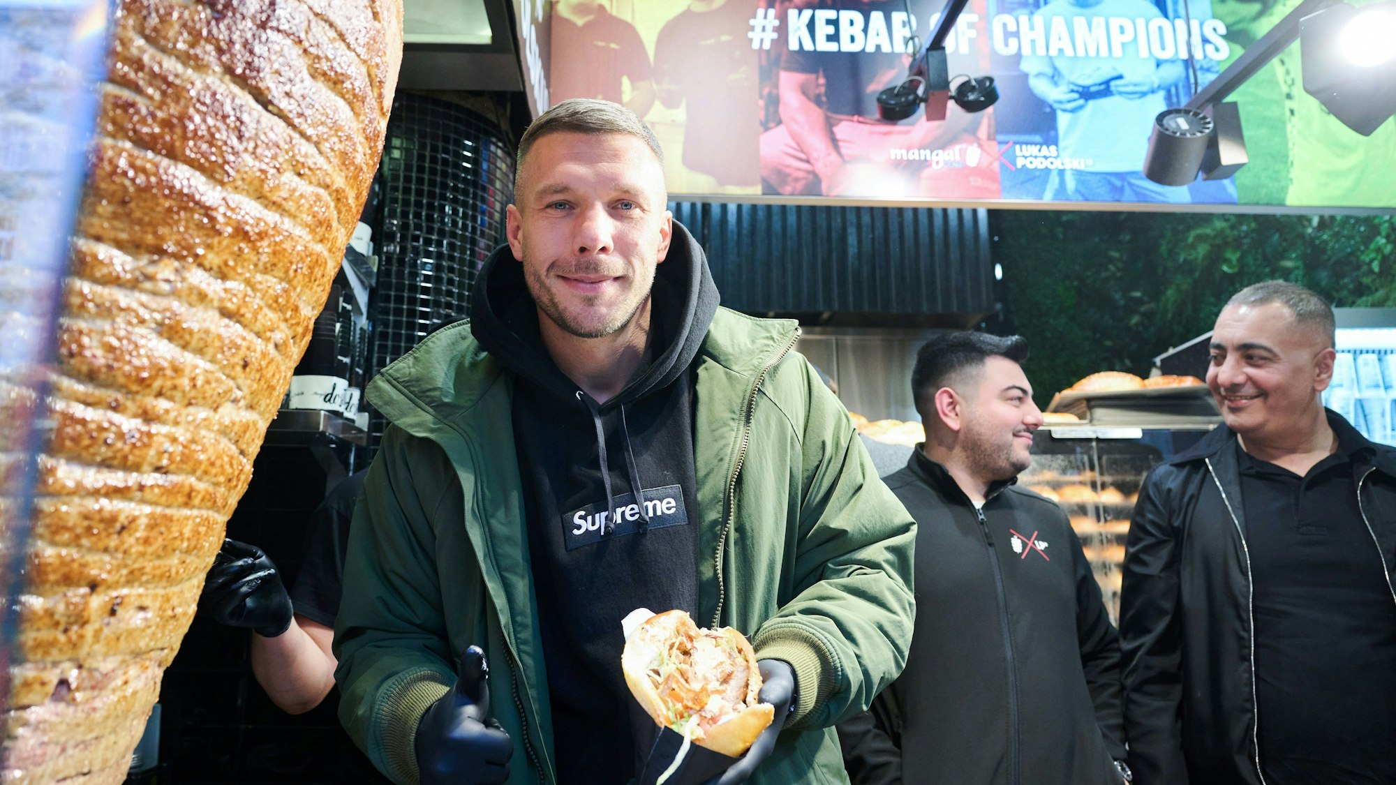 Lukas Podolski, Fußballprofi und Unternehmer, zeigt seinen ersten Döner.