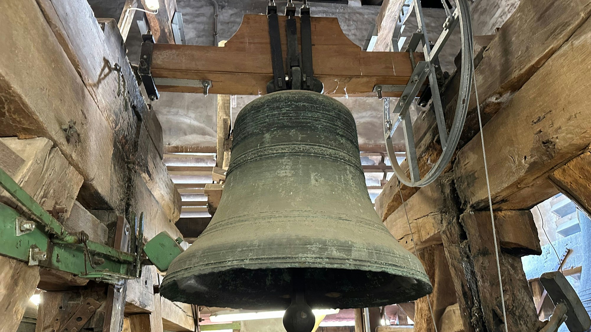 Eine alte Kirchenglocke in einem hölzernen Glockenstuhl.