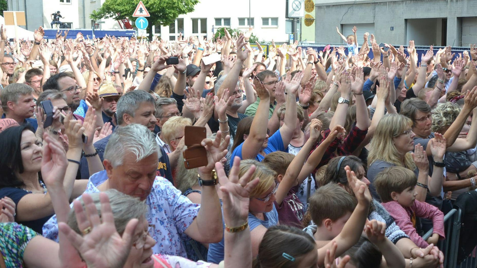 Frauen, Männer und Kinder drängen sich vor einer Bühne und klatschen im Takt zur Musik.