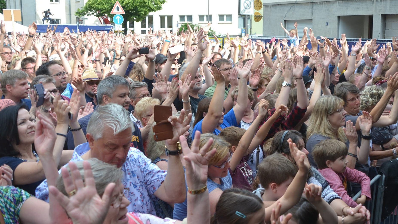 Frauen, Männer und Kinder drängen sich vor einer Bühne und klatschen im Takt zur Musik.