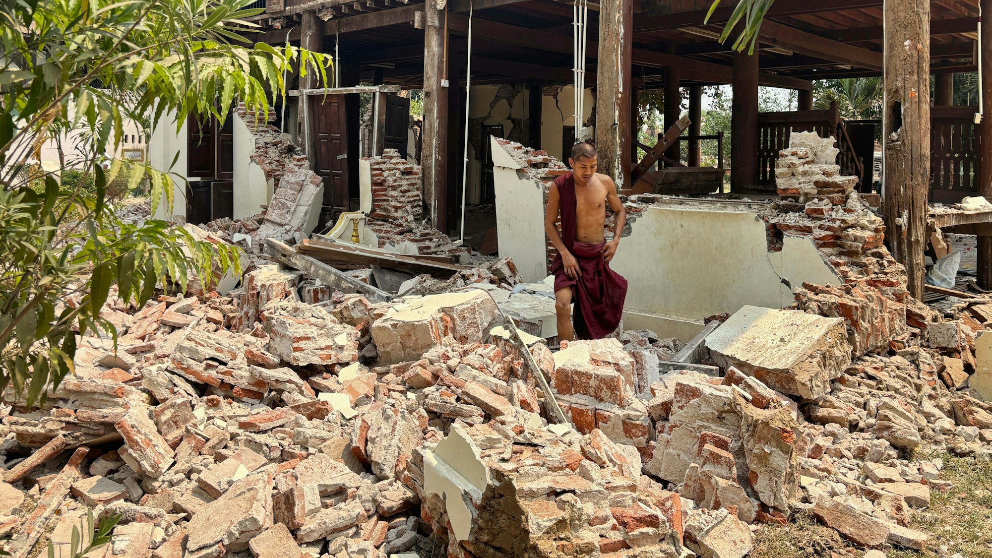 dpatopbilder - 28.03.2025, Myanmar, Naypyitaw: Ein buddhistischer Mönch steht in den Trümmern eines beschädigten Gebäudes in einer Klosteranlage nach einem Erdbeben. Foto: Aung Shine Oo/AP/dpa +++ dpa-Bildfunk +++