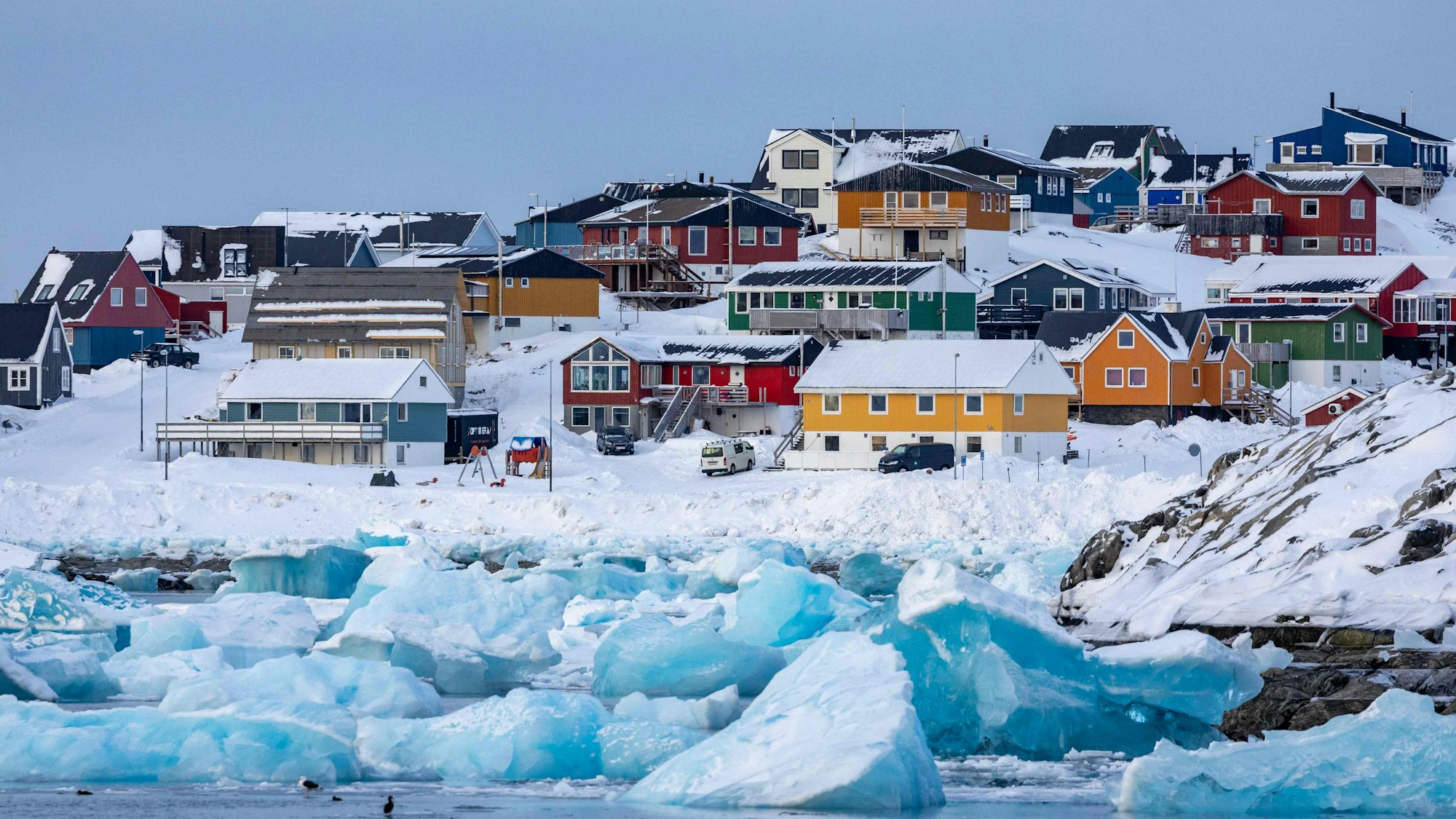 Eisberge schwimmen an der Küste vor Nuuk mit seinen bunten Häusern.