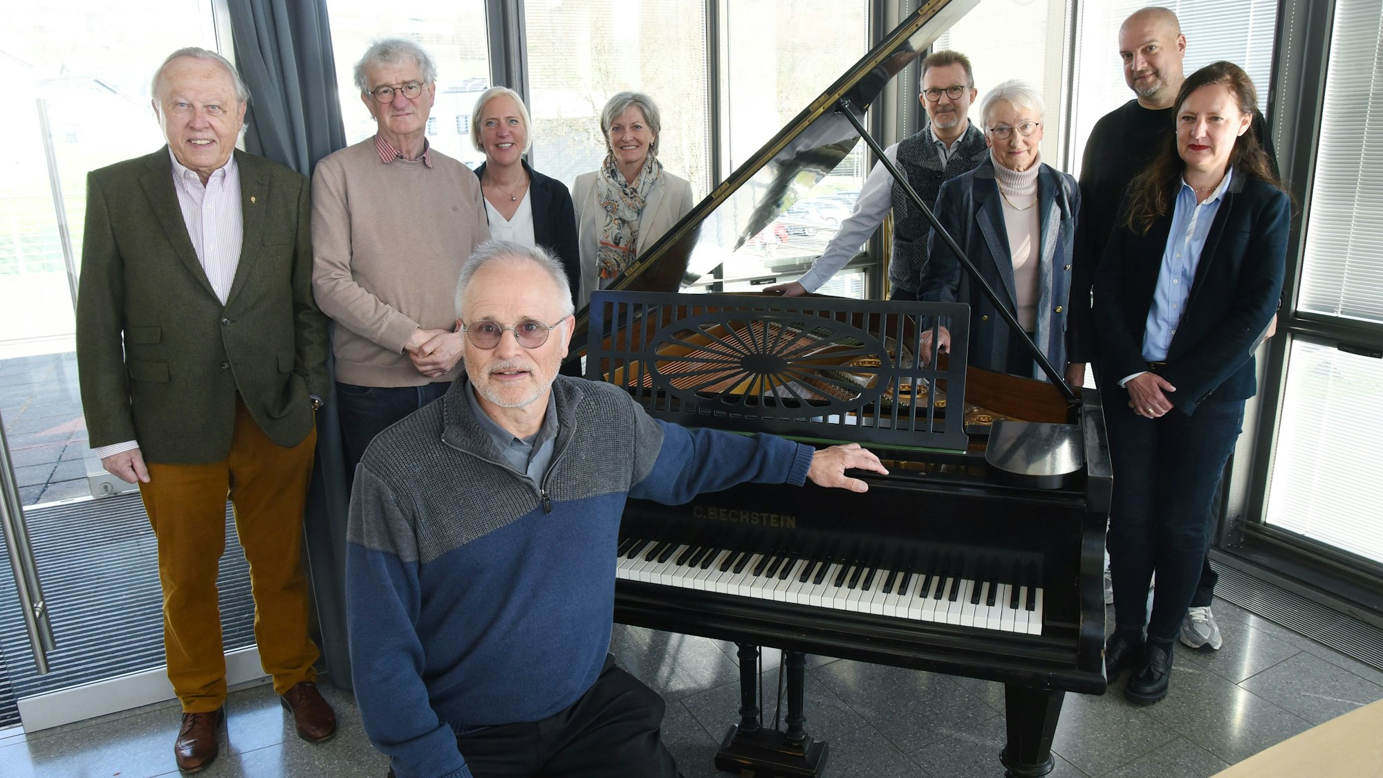 Das Foto zeigt die Organisatoren des Klavierfestivals mit dem musikalischen Leiter Falko Steinbach, der vor einem Flügel sitzt.