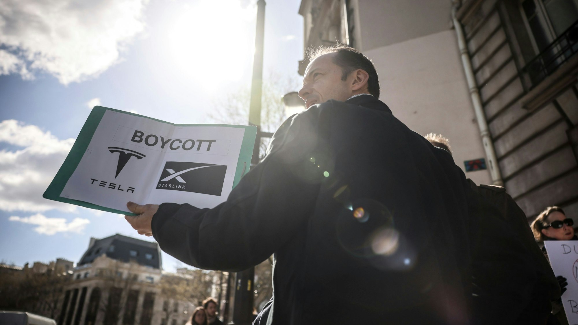 Ein Demonstrant hält ein Plakat, während er am Tesla Takedown Global Day of Action in der Nähe eines Tesla-Händlers in Paris teilnimmt.