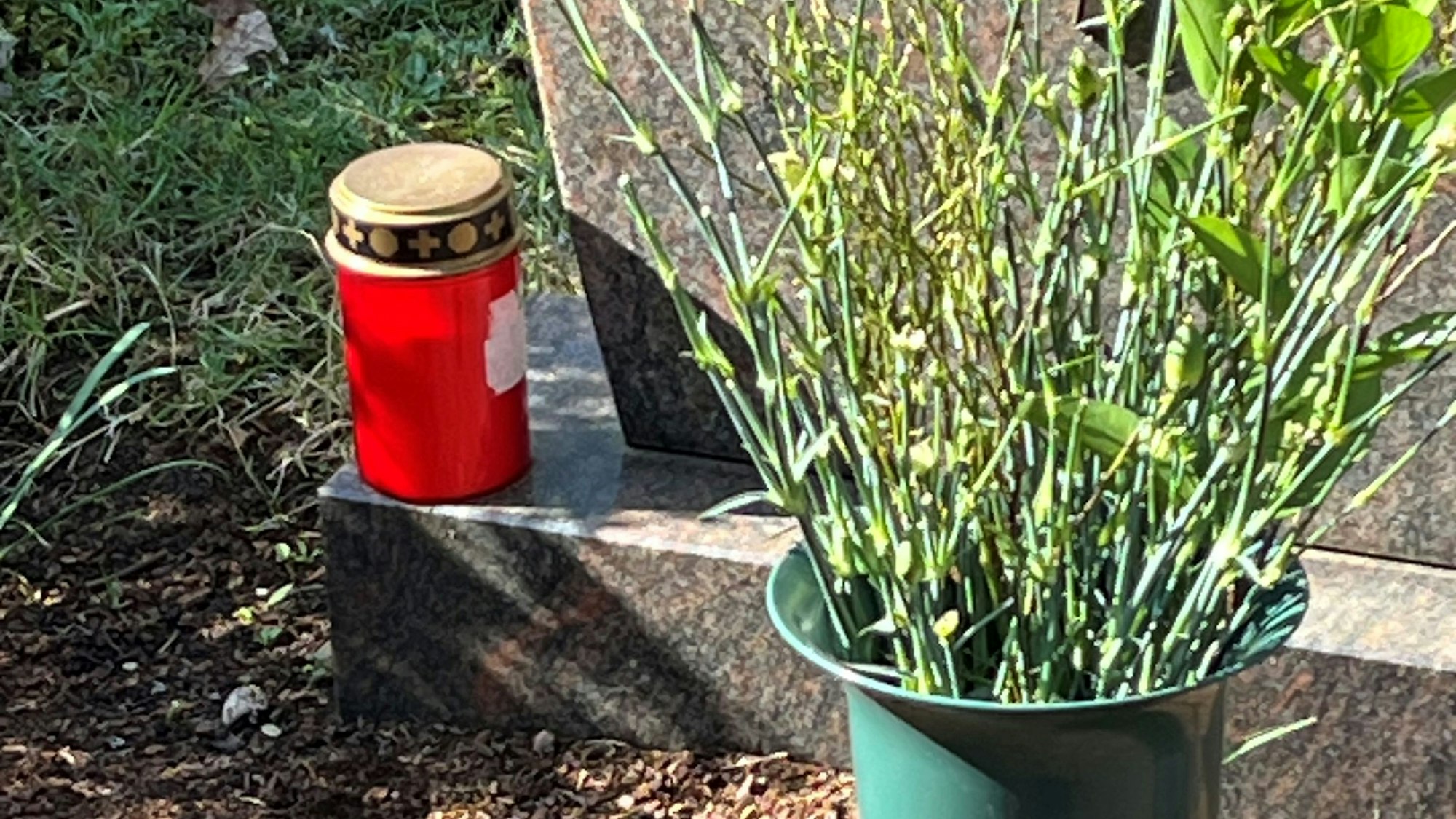 In einer Friedhofsvase seht ein Strauß, an dem die Blüten abgefressen sind.