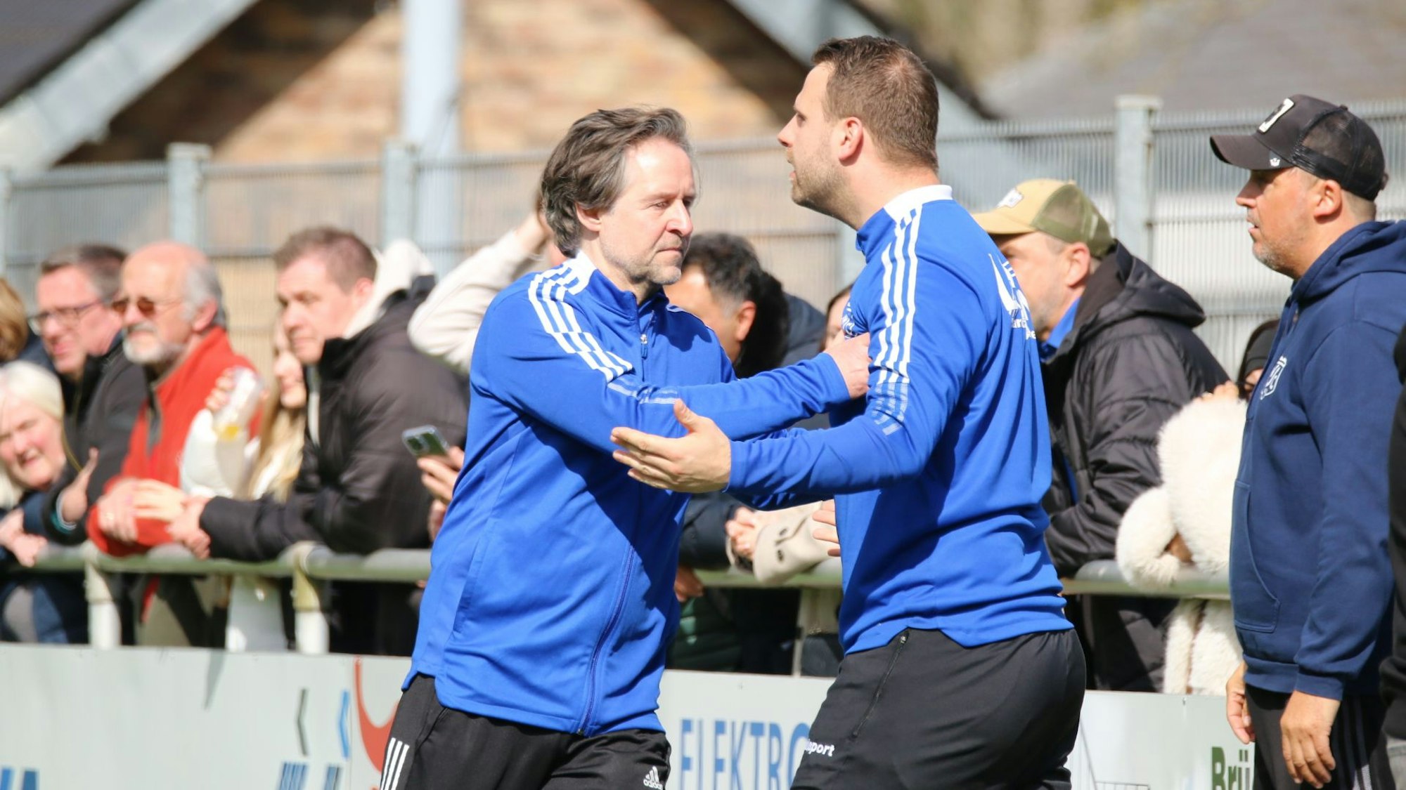 Der Trainer hält seinen Ersatztorwart an der Traingsjacke fest.