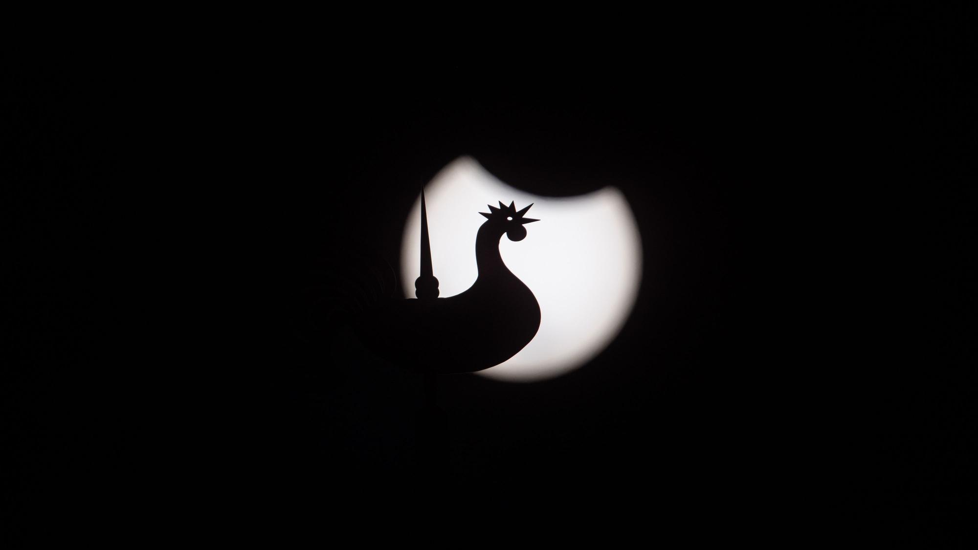 29.03.2025, Köln: Der Wetterhahn der Kirche St. Bruno in Klettenberg ist als Silhouette vor der teilweise verdunkelten Sonnenschreibe zu sehen. Die Sonne wird bei einer partiellen Sonnenfinsternis am Rand von der Mondscheibe bedeckt. Hier in der Region beträgt die maximale Verdunkelung 20%. Aufgenommen mit 840mm Brennweite und einem Sonnenfilter. Foto: Matthias Heinekamp29.03.2025, Köln: Die Sonne wird bei einer partiellen Sonnenfinsternis am Rand von der Mondscheibe bedeckt. Hier in der Region beträgt die maximale Verdunkelung 20%. Aufgenommen mit 840mm Brennweite und einem Sonnenfilter. Foto: Matthias Heinekamp29.03.2025, Köln: Die Sonne wird bei einer partiellen Sonnenfinsternis am Rand von der Mondscheibe bedeckt. Hier in der Region beträgt die maximale Verdunkelung 20%. Aufgenommen mit 840mm Brennweite und einem Sonnenfilter. Foto: Matthias Heinekamp