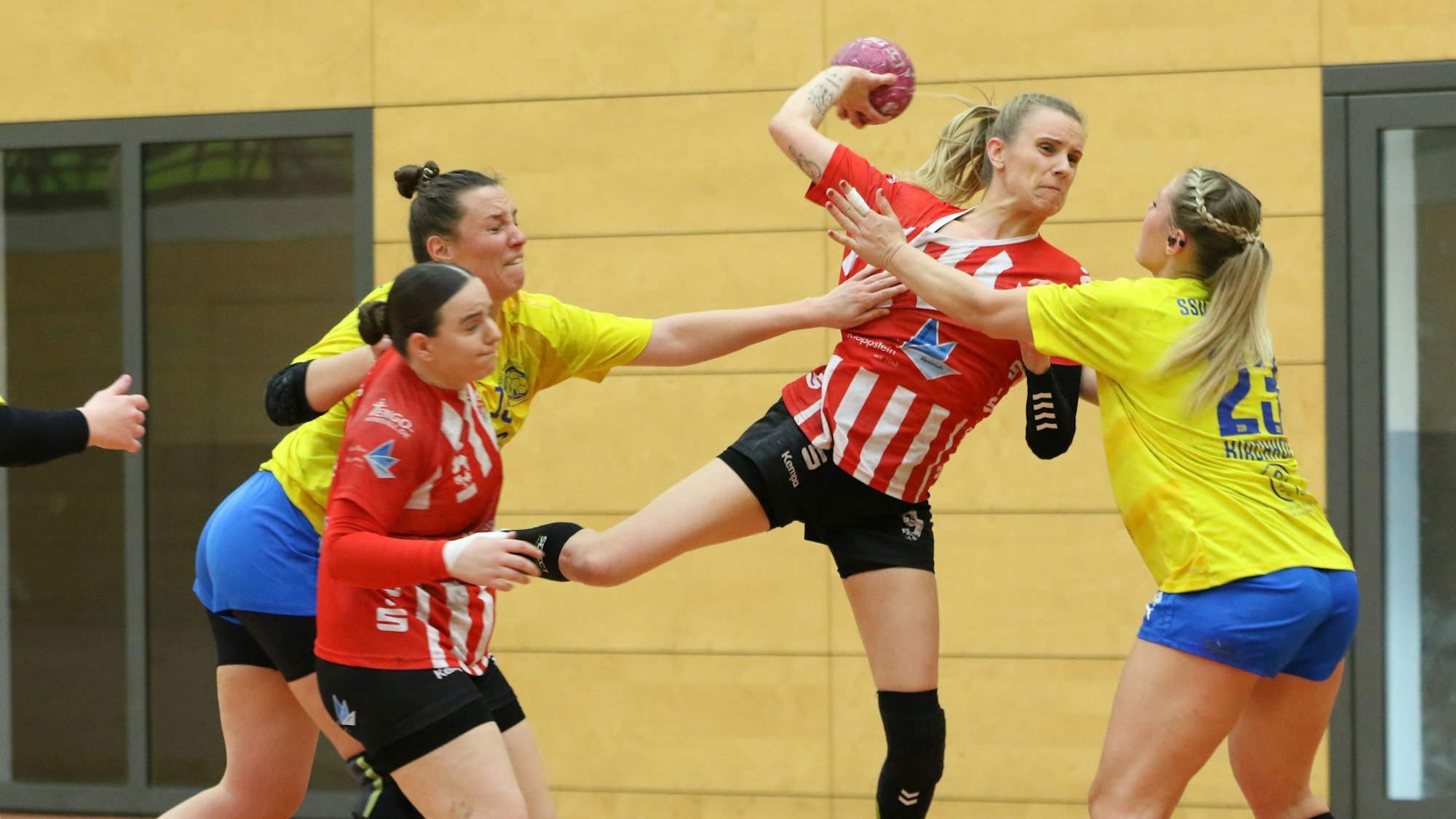 Corinna Schmitz beim Wurf. Eine Gegenspielerin blockt sie, eine andere greift nach ihrem Trikot.