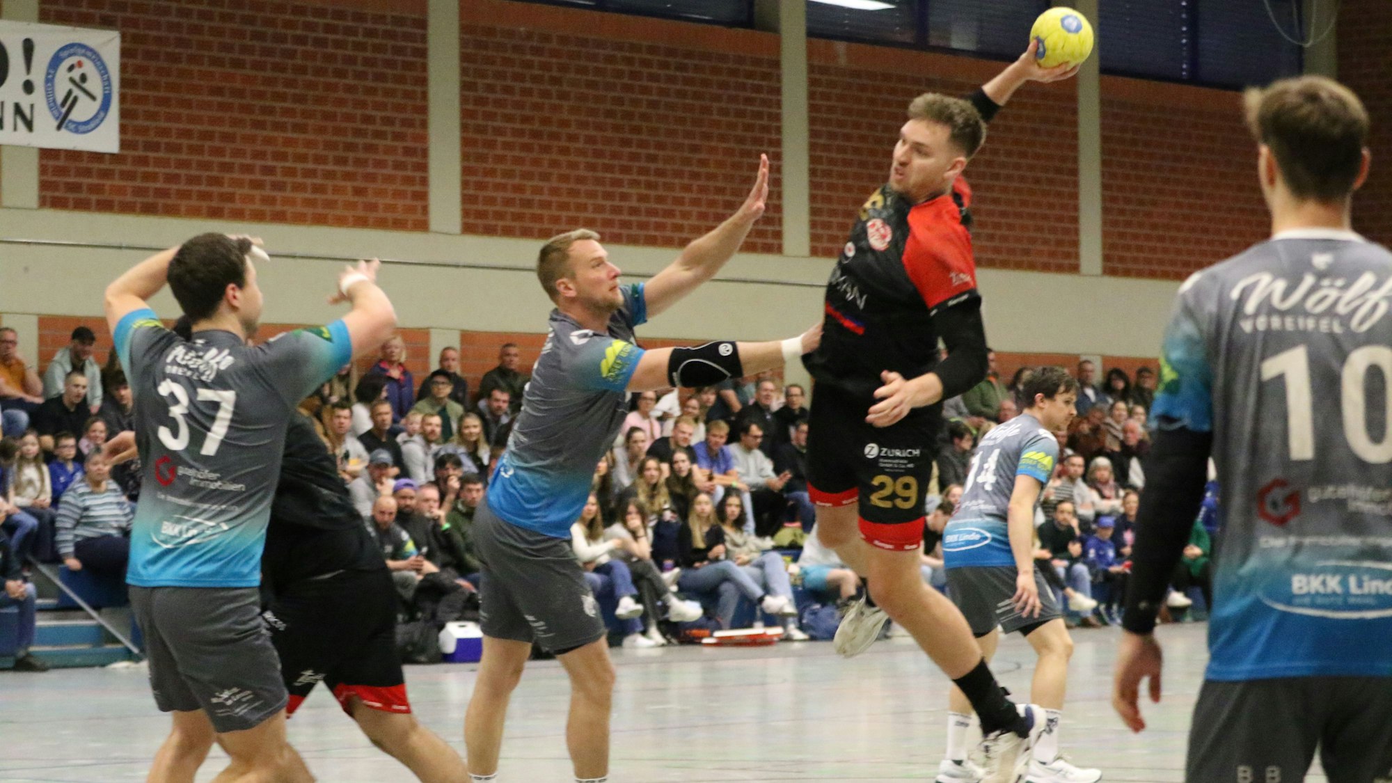 Ein Spieler des TV Palmersheim beim Wurf. Im Hintergrund kann man die gut besuchte Sporthalle in Heimerzheim erkennen.