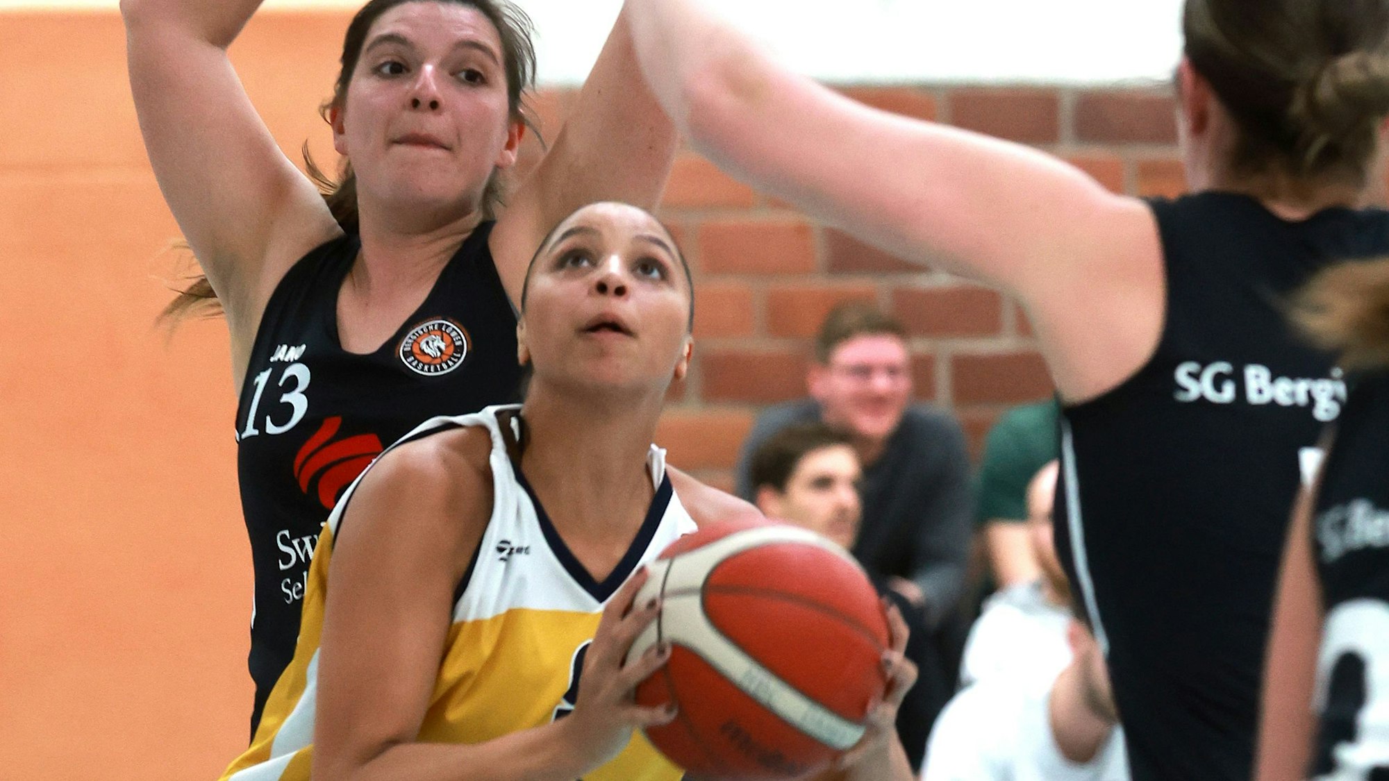 Das Foto zeigt eine Basketballerin im gelben Trikot des Hürther BC, die den Korb anvisiert.