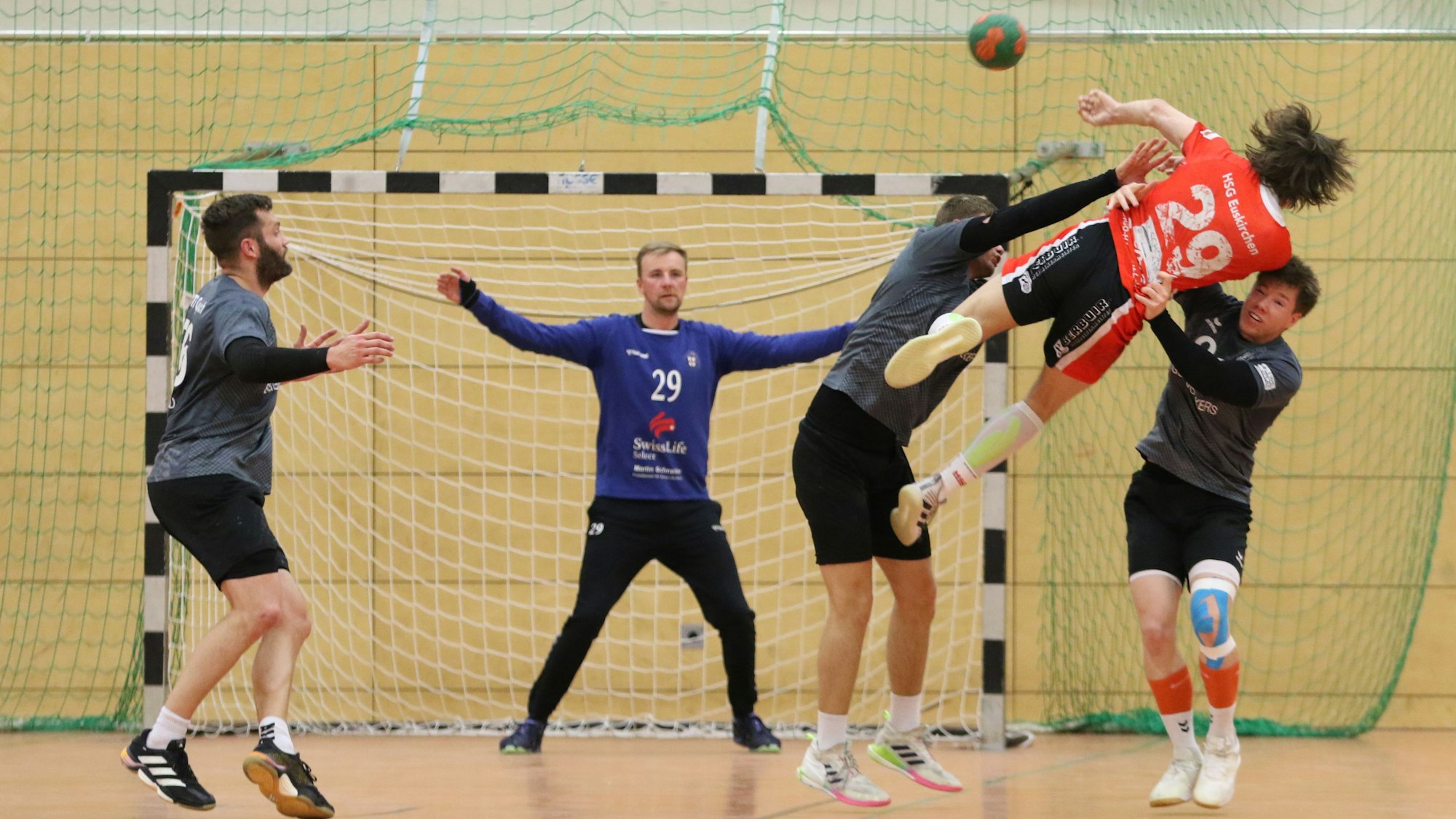 Euskirchens Jarl Schramm liegt quer in der Luft. Ein Gegenspieler greift von unten nach ihm, ein anderer versucht den Ball abzuwehren.