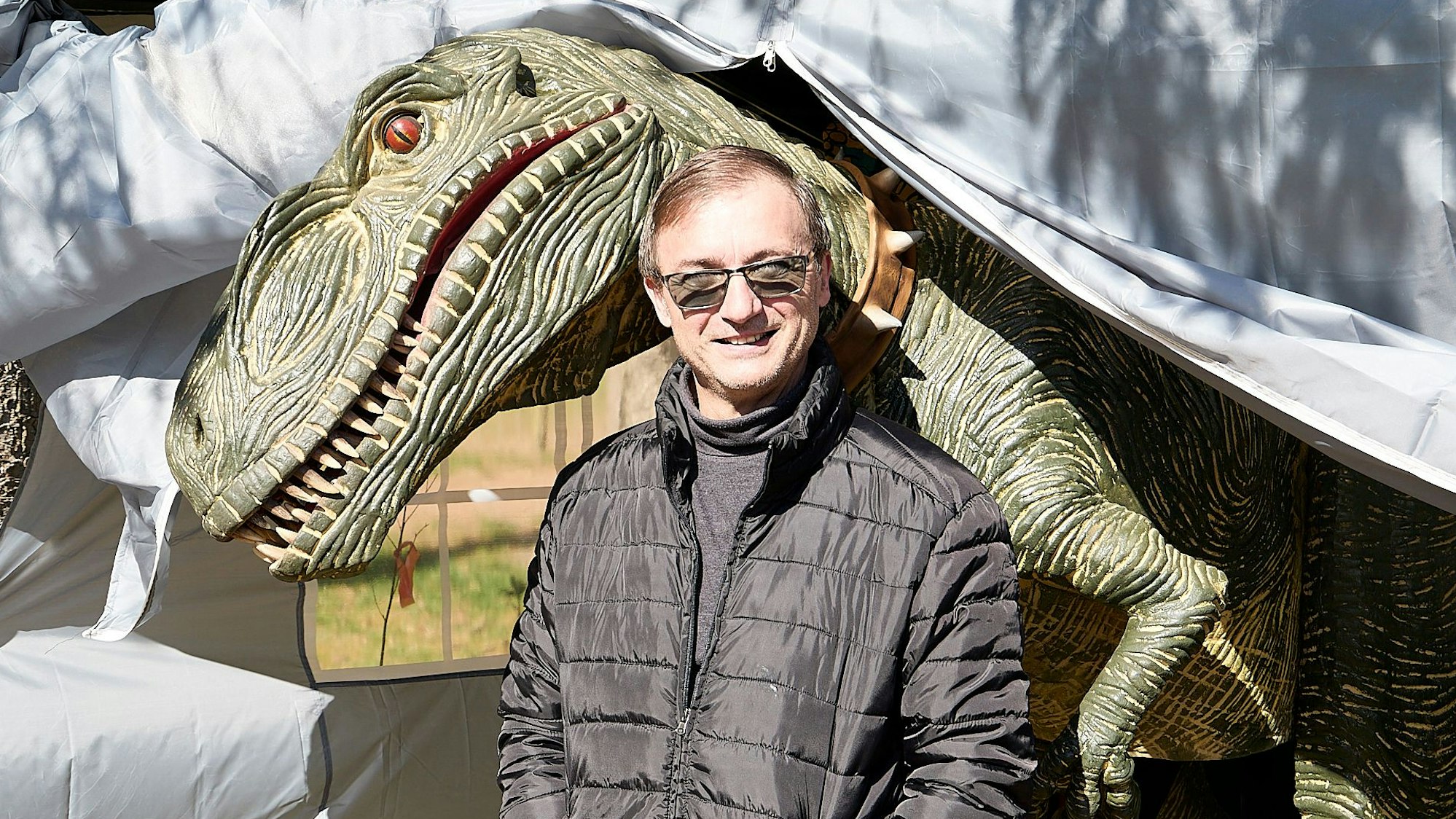 Dieter Czech steht vor einem T-Rex. Der Dinosaurier ist ein Kostüm, mit dem Czech auf vielen Festen für Aufsehen sorgt.