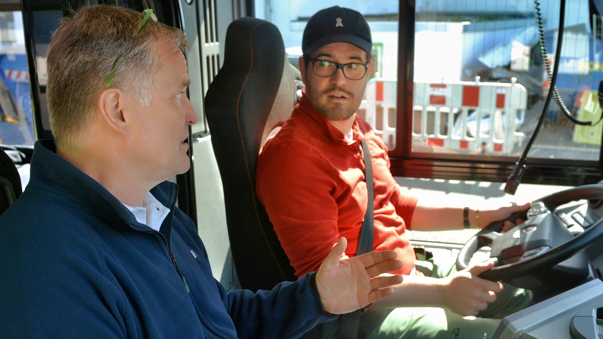 Ingo Krewitt sitzt auf einem Beifahrersitz, Flaksbaum Moll am Steuer eines Busses.