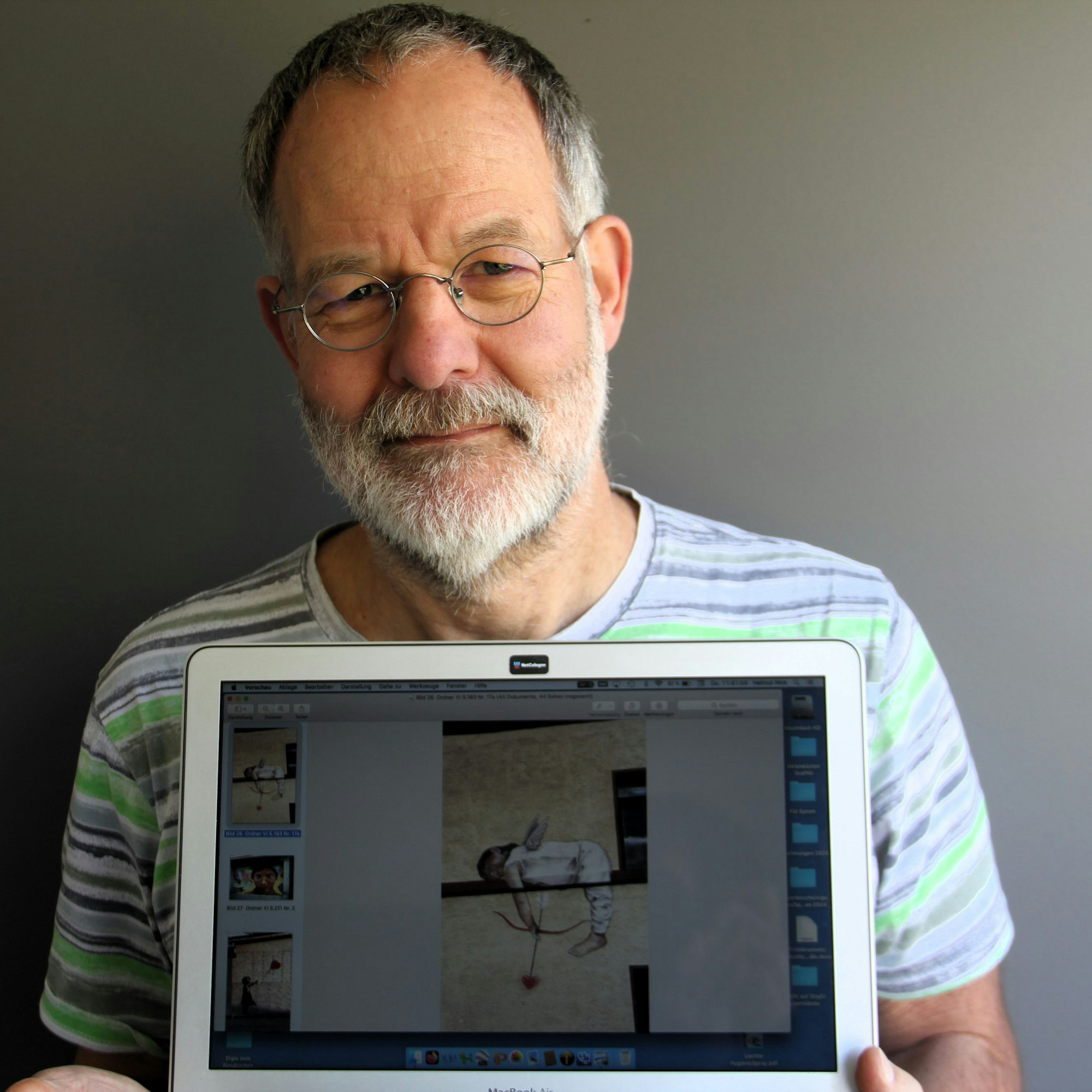 Ein Mann hält einen Laptop, auf dem ein Graffiti zu sehen ist.