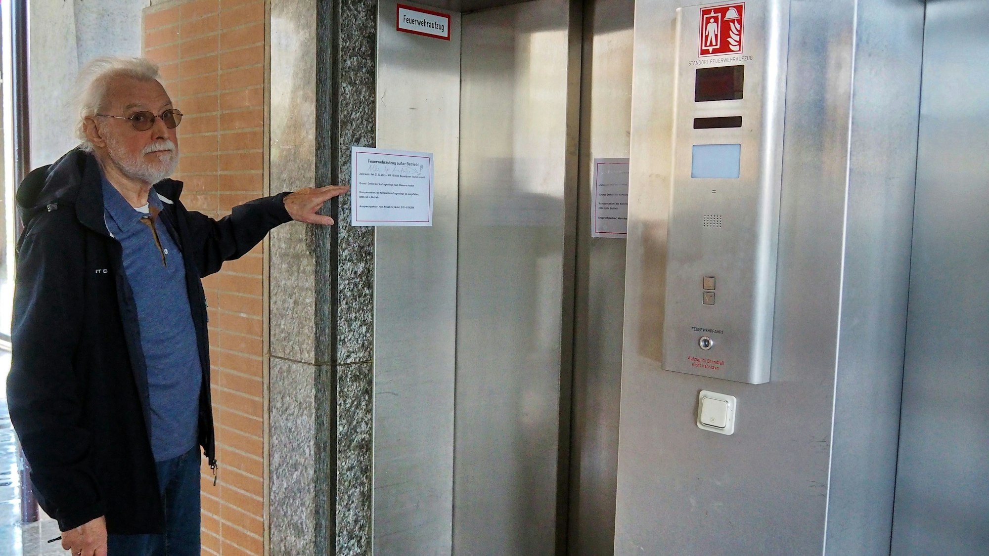 Ein Mann zeigt auf einen defekten Aufzug.