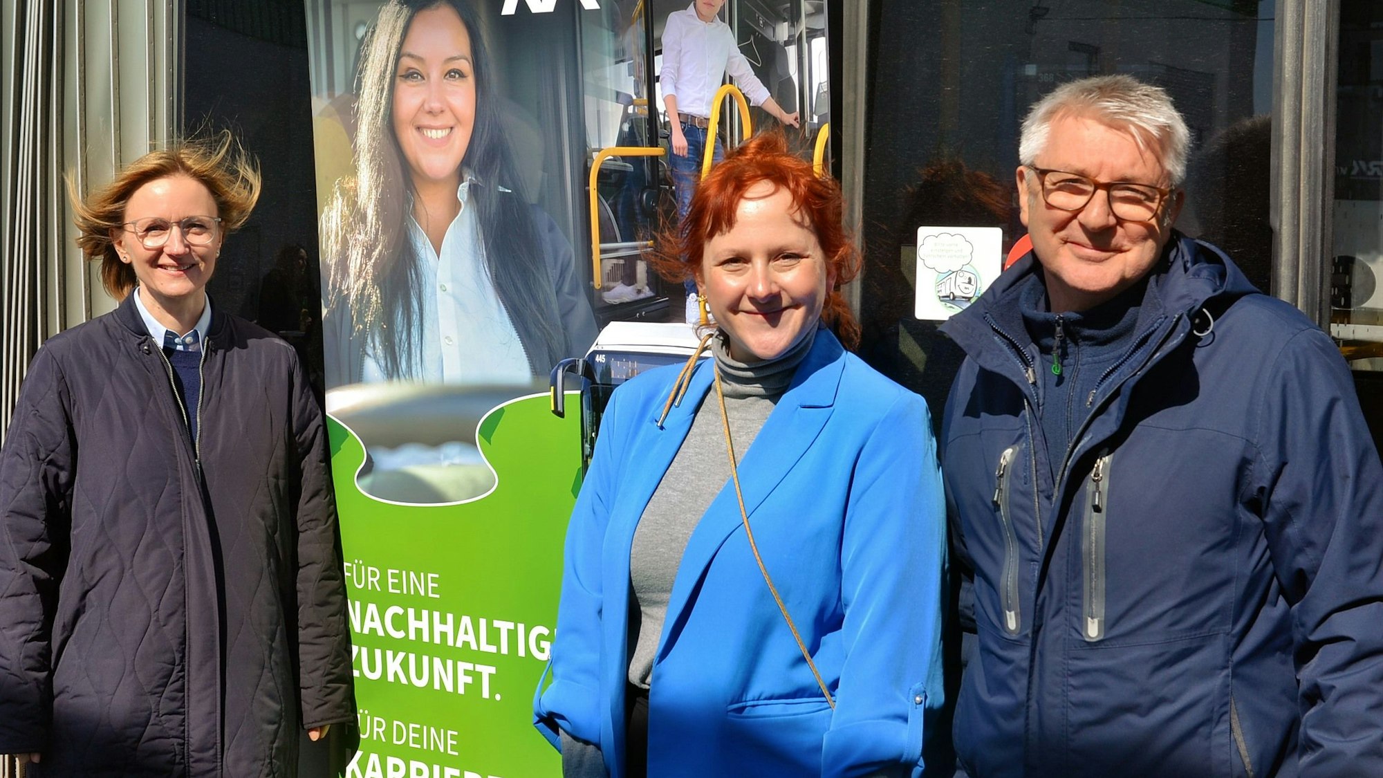 Nicole Thieler, Nadine Otto und Egbert Wagener stehen vor einem Plakat, auf dem für eine Ausbildung bei der RVK geworben wird.