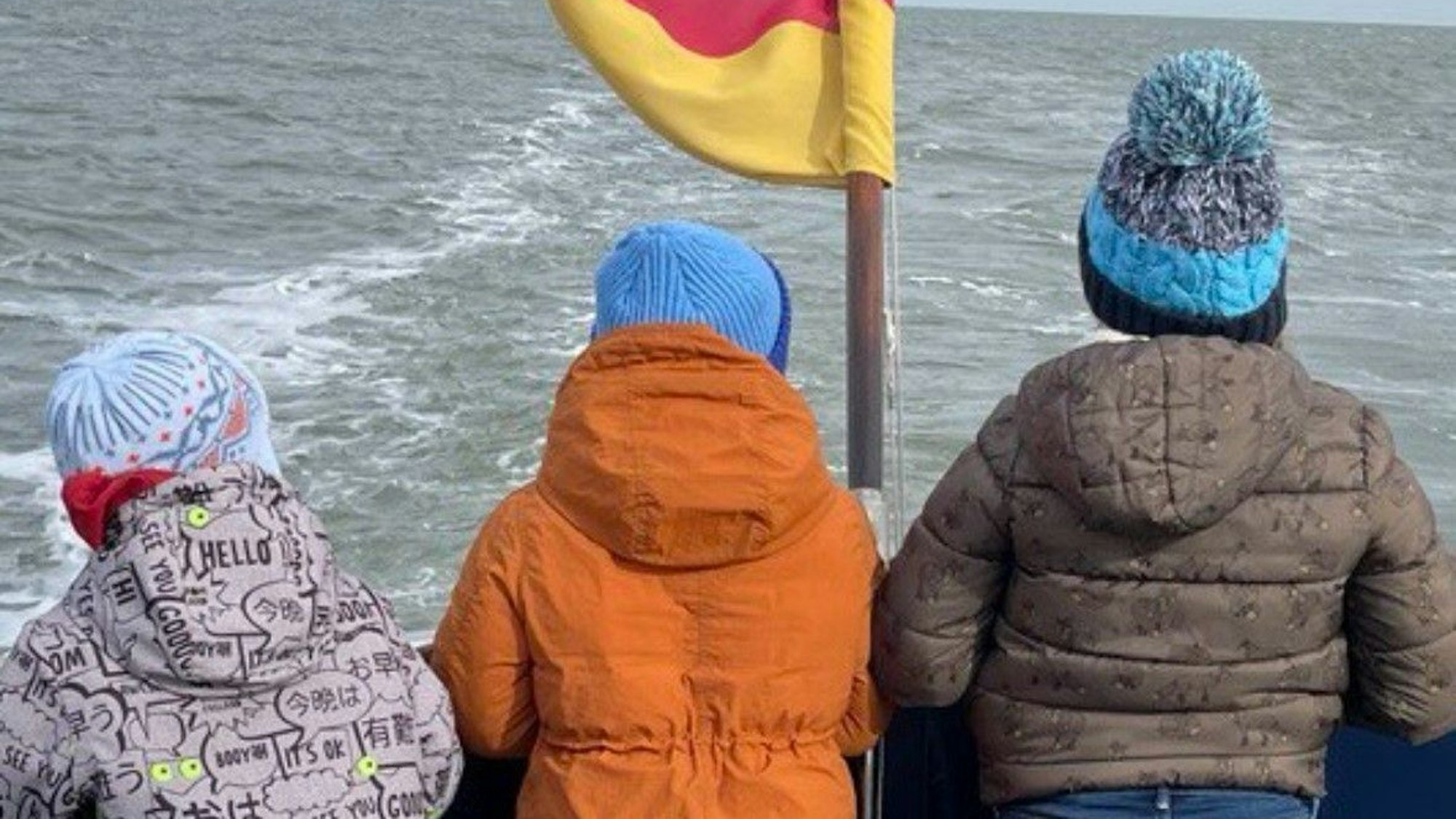 Auf dem Bild sind die drei kleinen Kinder von Olesia S. von hinten bei der Seebestattung ihrer Mutter zu sehen.