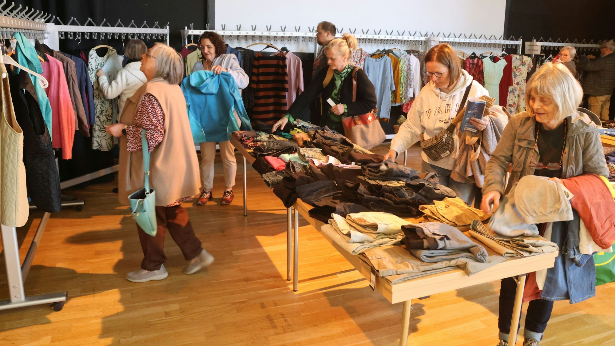Mehrere Frauen stöbern bei einem Kleidermarkt.