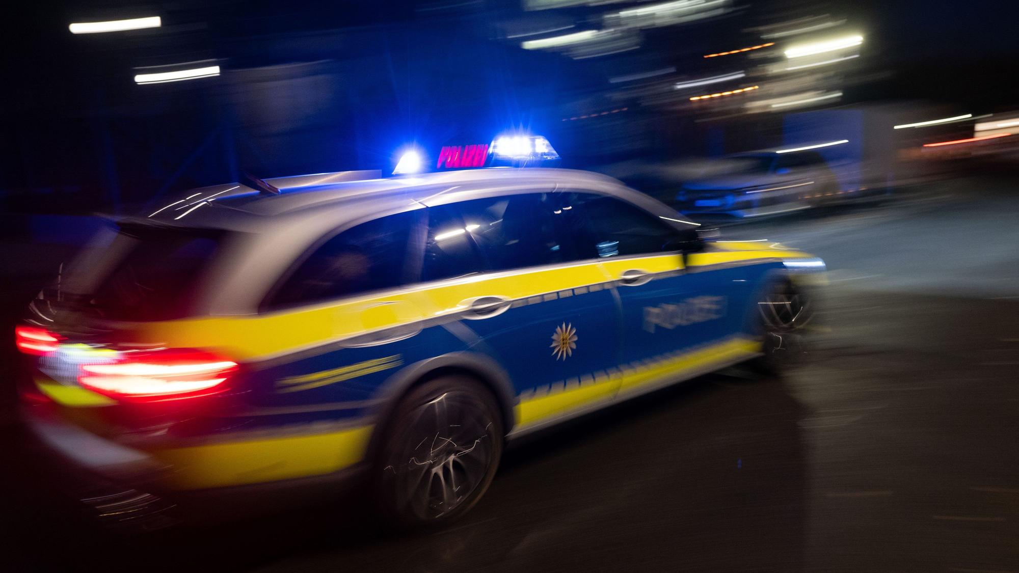 Ein Polizeifahrzeug fährt mit Blaulicht an einem Gebäude vorbei.