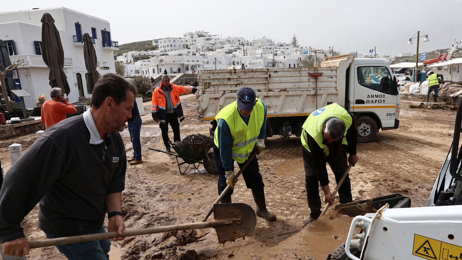 Auf der Ägäisinsel Paros schaufeln Helfer Schlamm von den Straßen.