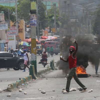 Ein Mann gestikuliert auf einer Straße, die durch brennende Reifen und Trümmer blockiert ist, während einer Demonstration, die den Rücktritt des Übergangspräsidentenrates fordert, in Port-au-Prince, Haiti.