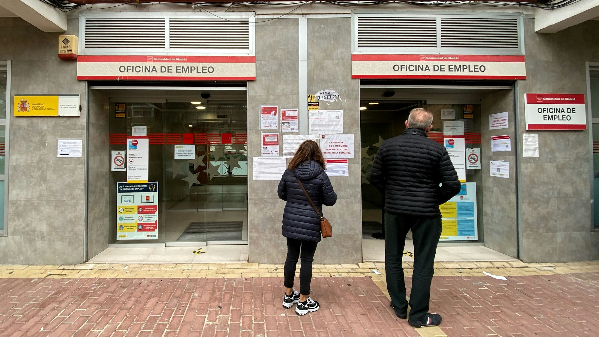 Eine Frau und ein Mann stehen vor einem Arbeitsamt in Madrid.