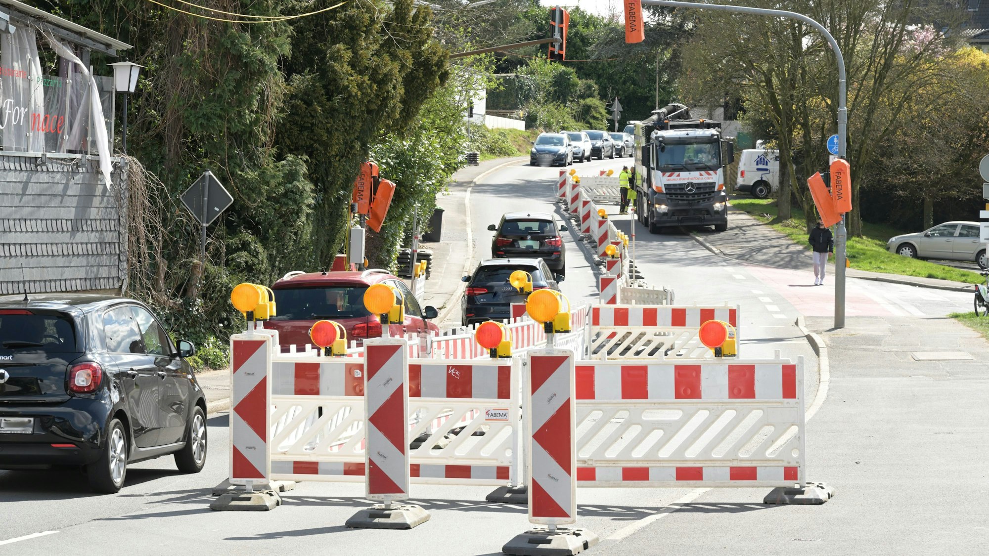 Eine Baustelle auf der Straße. Eine Fahrbahn ist mit rot-weißen Baken abgesperrt.