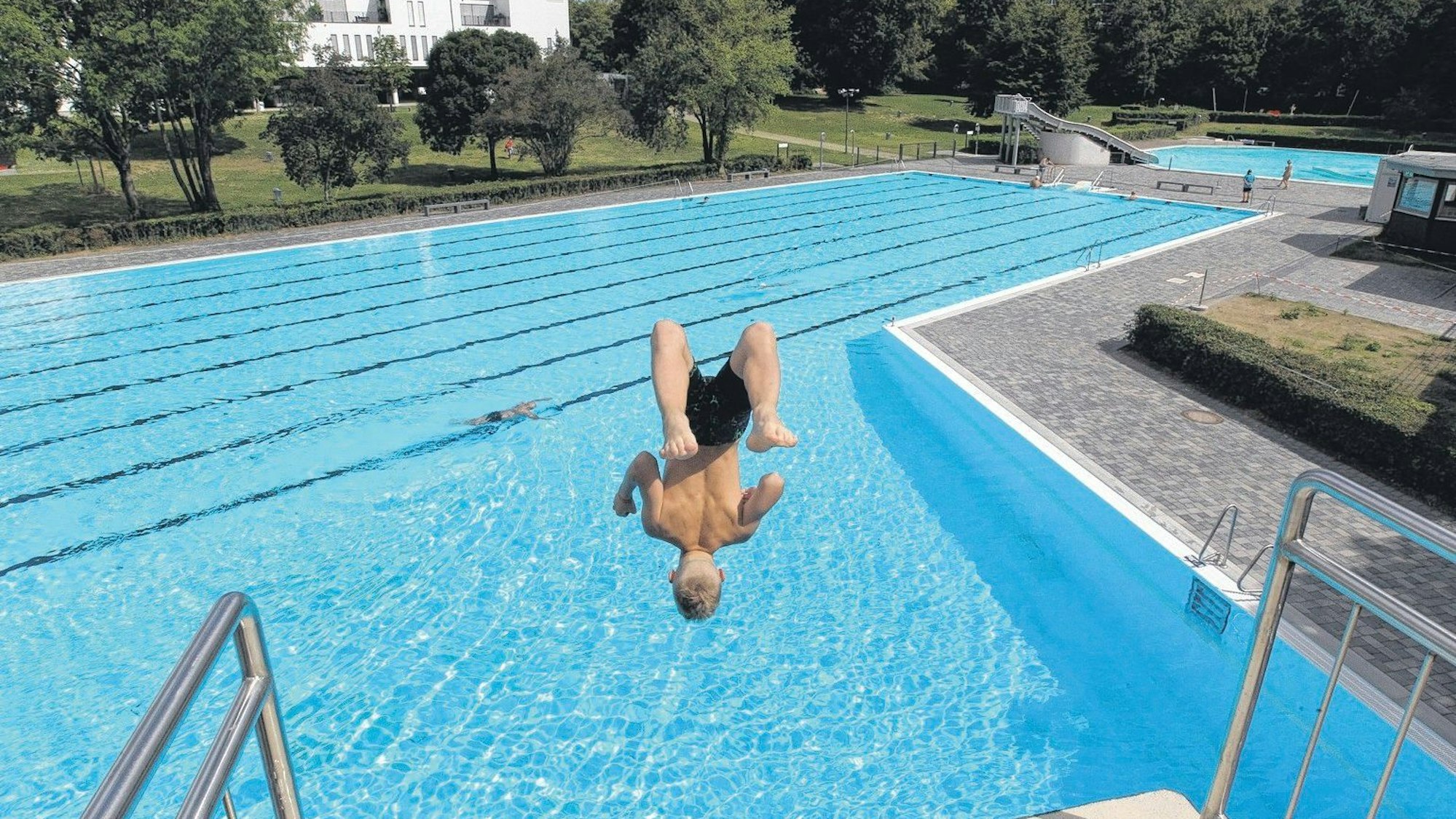 Ein Mann springt vom Sprungturm eines Freibads