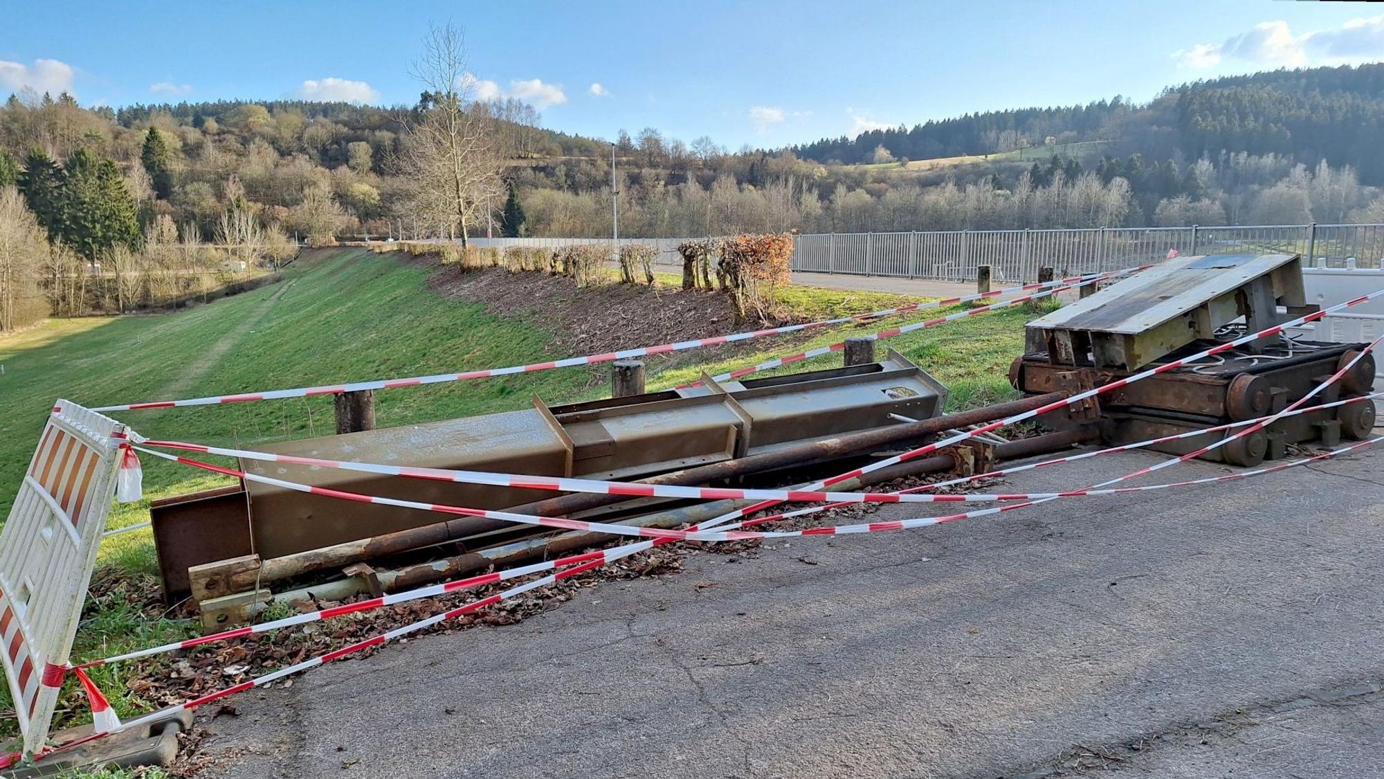 Ein Betriebsschütz der Stauanlage am Kronenburger See, das bei der Flutkatastrophe 2021 zerstört wurde, liegt am Rand des Staudamms. Der Bereich ist mit rot-weißem Flatterband abgesperrt.