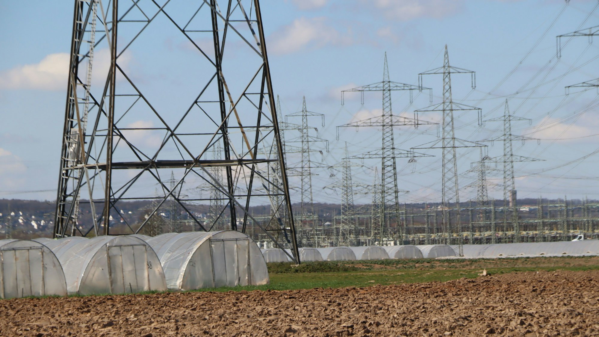 Zu sehen sind Äcker, Gewächshaustunnel und Strommasten.
