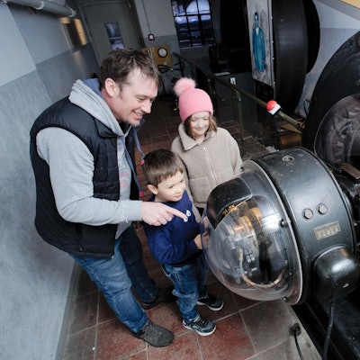Ein Mann und zwei Kinder an einer großen Maschine.