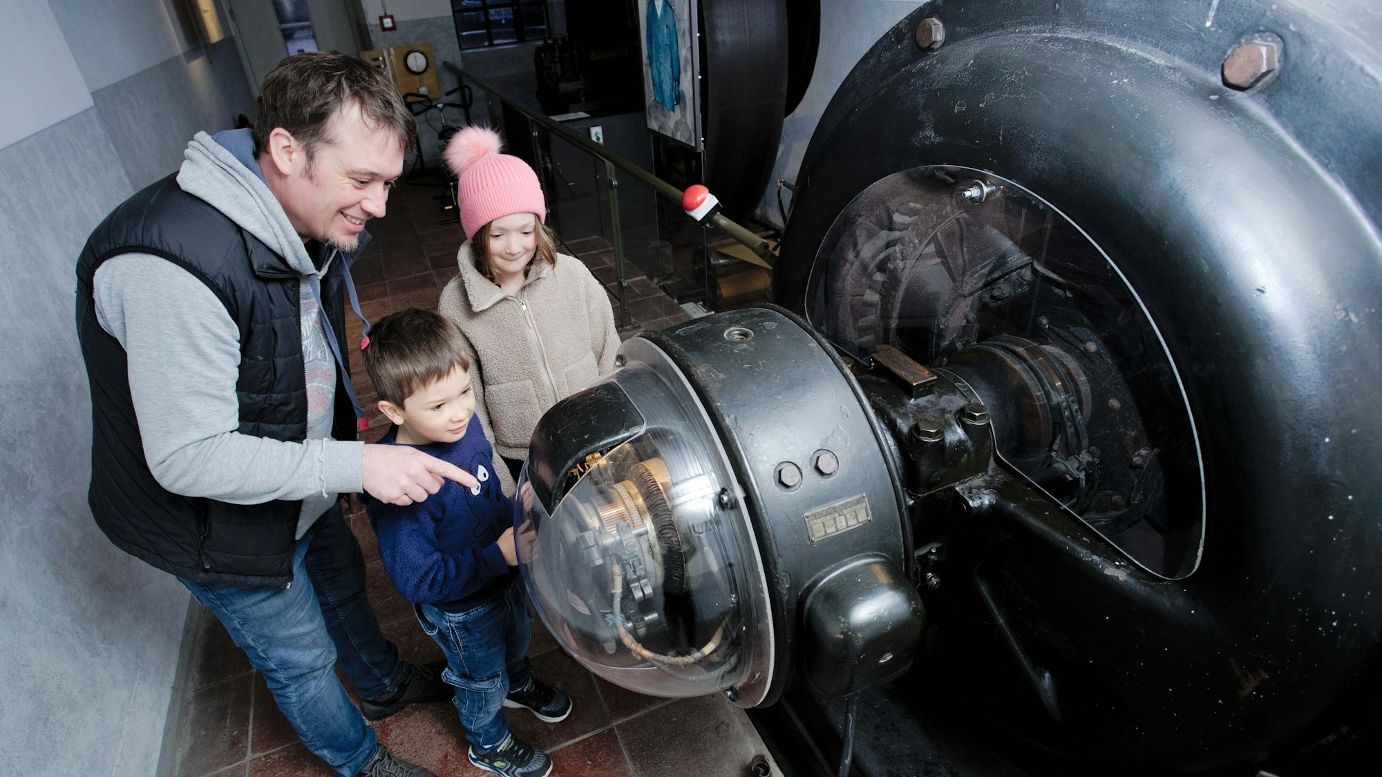 Eine Familie steht an einer alten Turbine des Industriemuseums