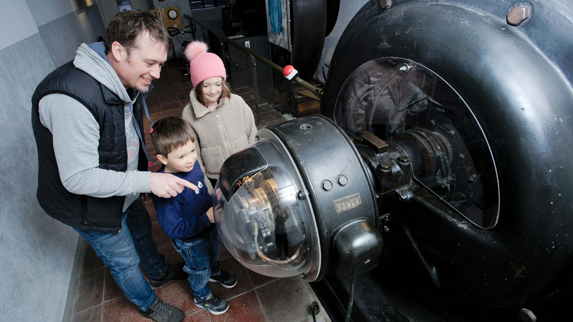 Ein Mann und zwei Kinder an einer großen Maschine.